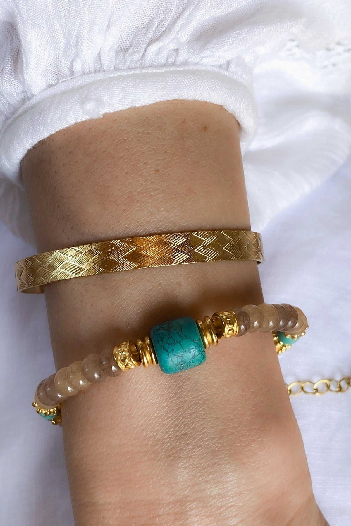 Gold elegant Cuff Bracelet with a metallic straw-patterned band, shown alongside a beaded bracelet with a turquoise accent