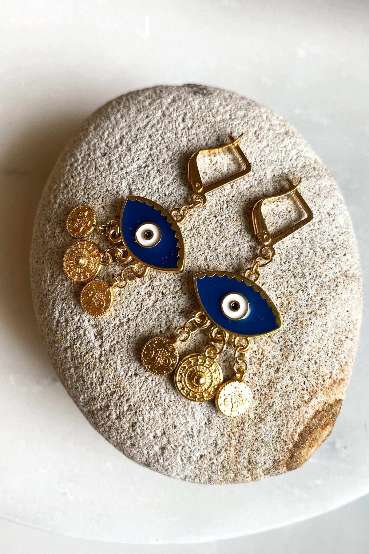 Gold evil eye earrings with deep blue enamel eyes, gold-toned metal and dangling embossed coin charms