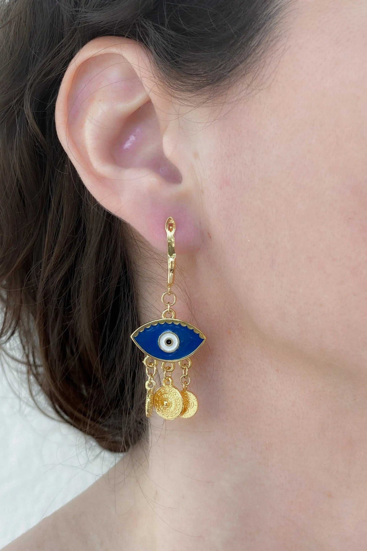 Gold evil eye earrings with blue enamel eye motif, gold-toned dangling chains and textured coin charms