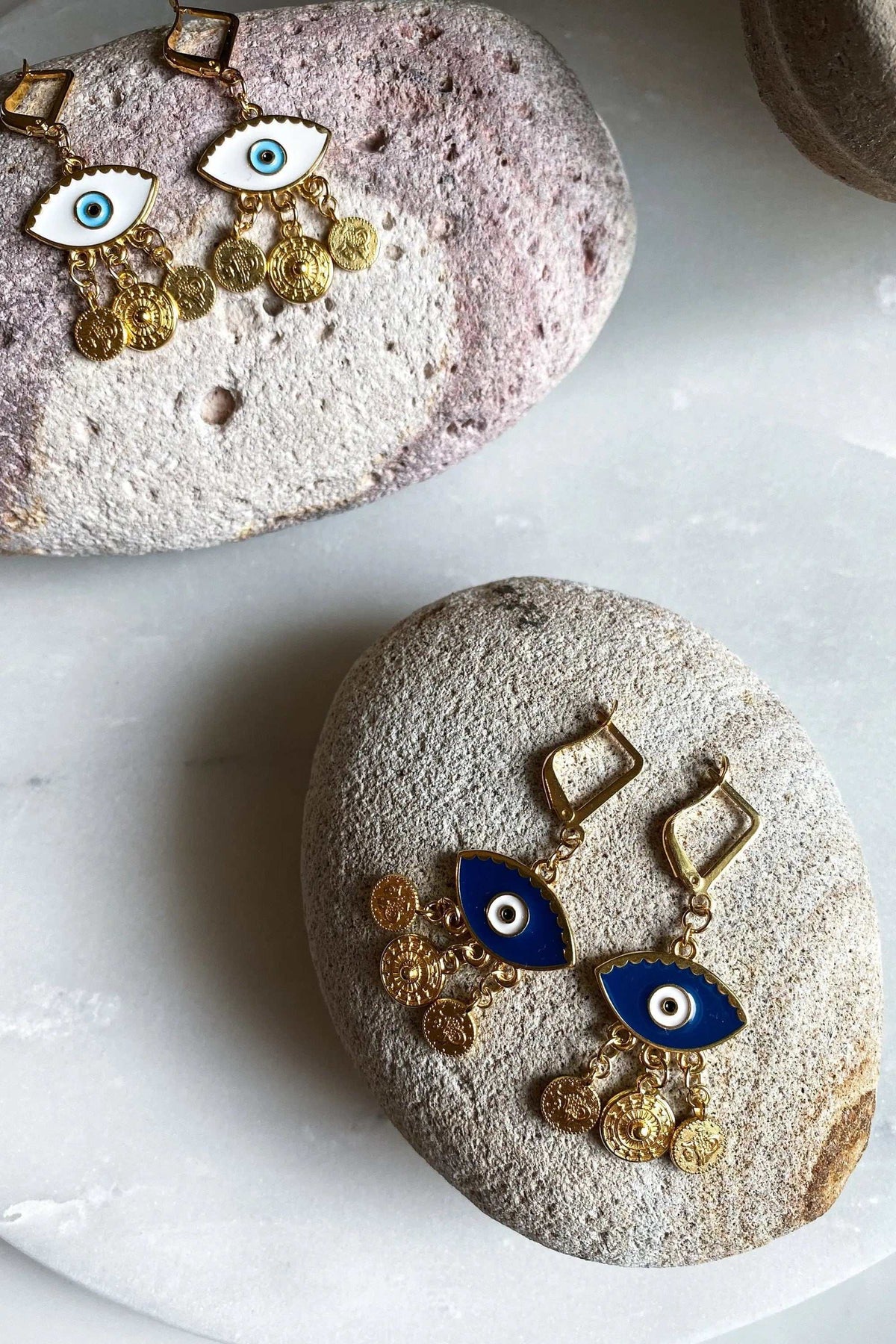 Gold evil eye earrings with gold-toned metal, blue and white eye motifs, and dangling coin charms