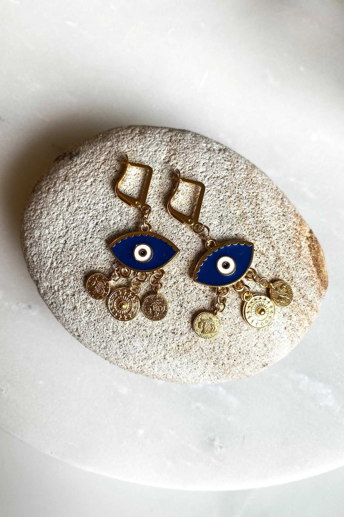 Gold evil eye earrings in gold-tone metal with vivid blue enamel eyes and dangling coin charms