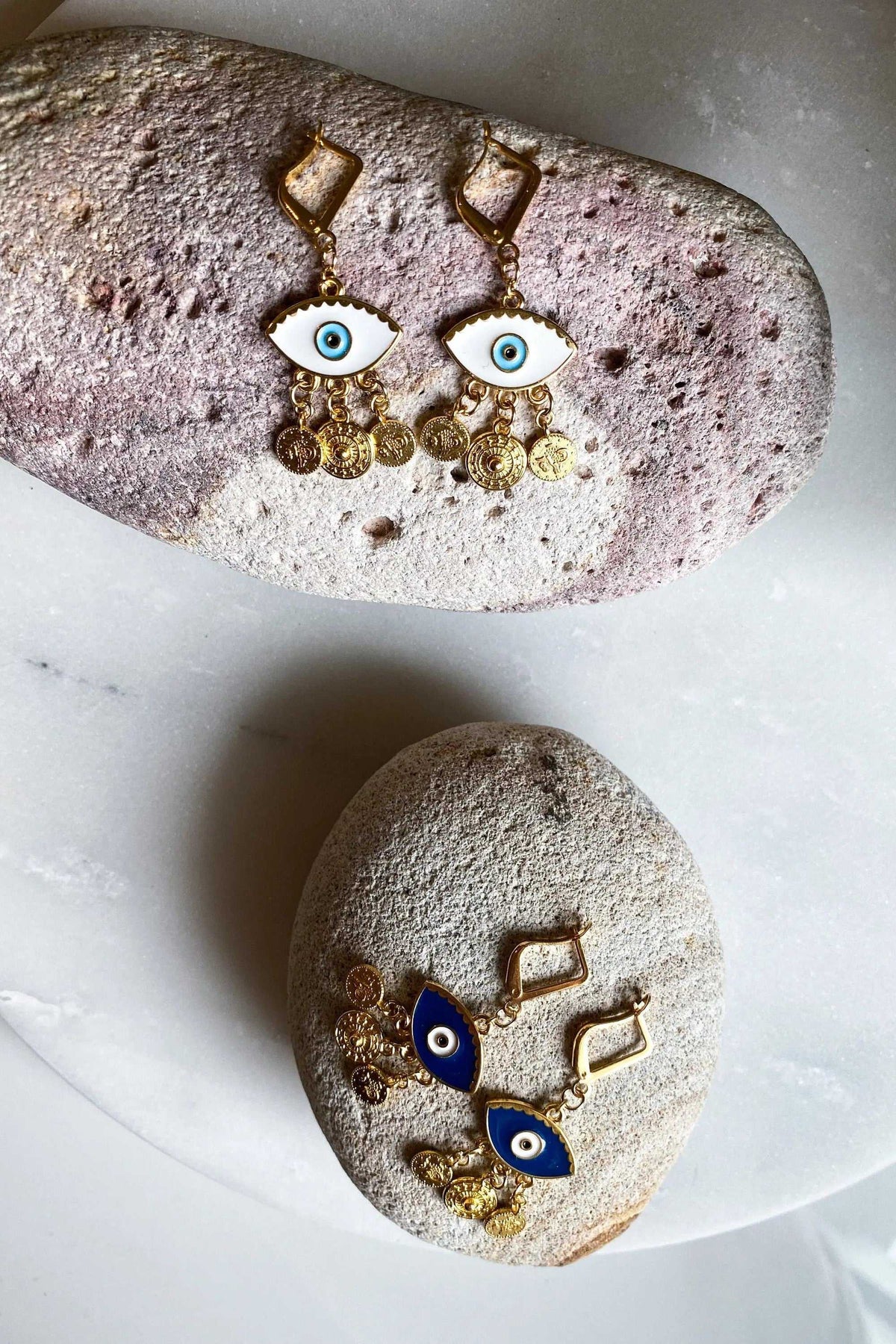 Gold evil eye earrings with white and blue enamel eyes, gold-tone geometric hooks and dangling coin charms