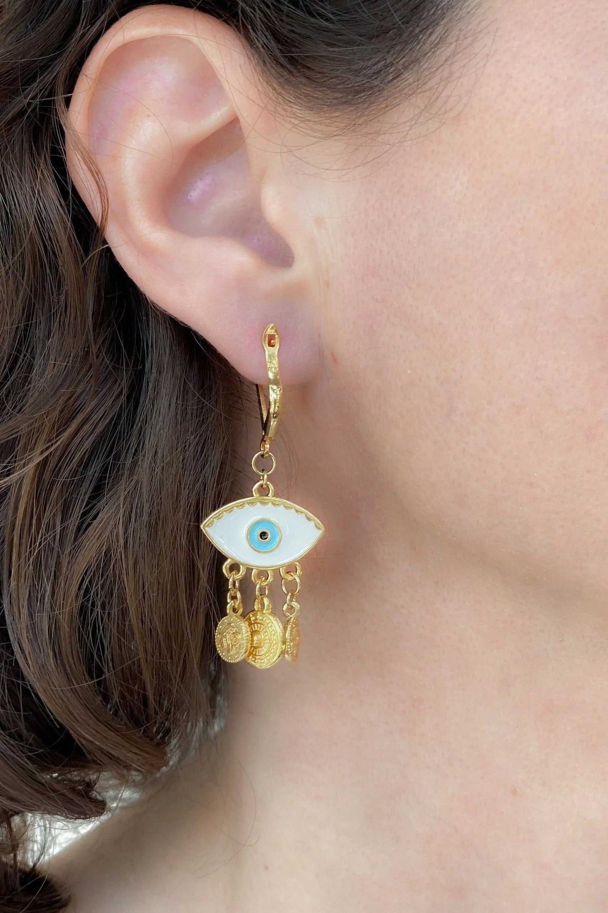 Gold evil eye earrings with white enamel eye motif, turquoise center, and dangling gold coin charms