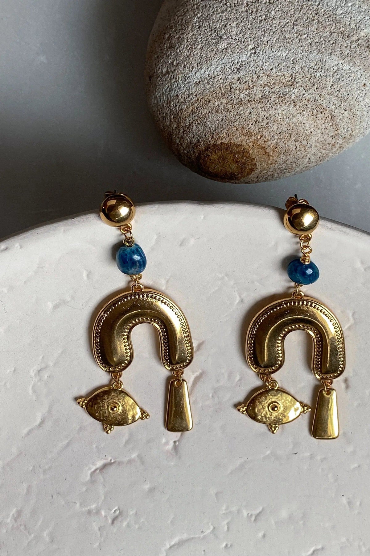 Gold Gypsy Earrings in ornate gold-tone metal with blue beads, featuring arched shapes and dangling eye and cone charms