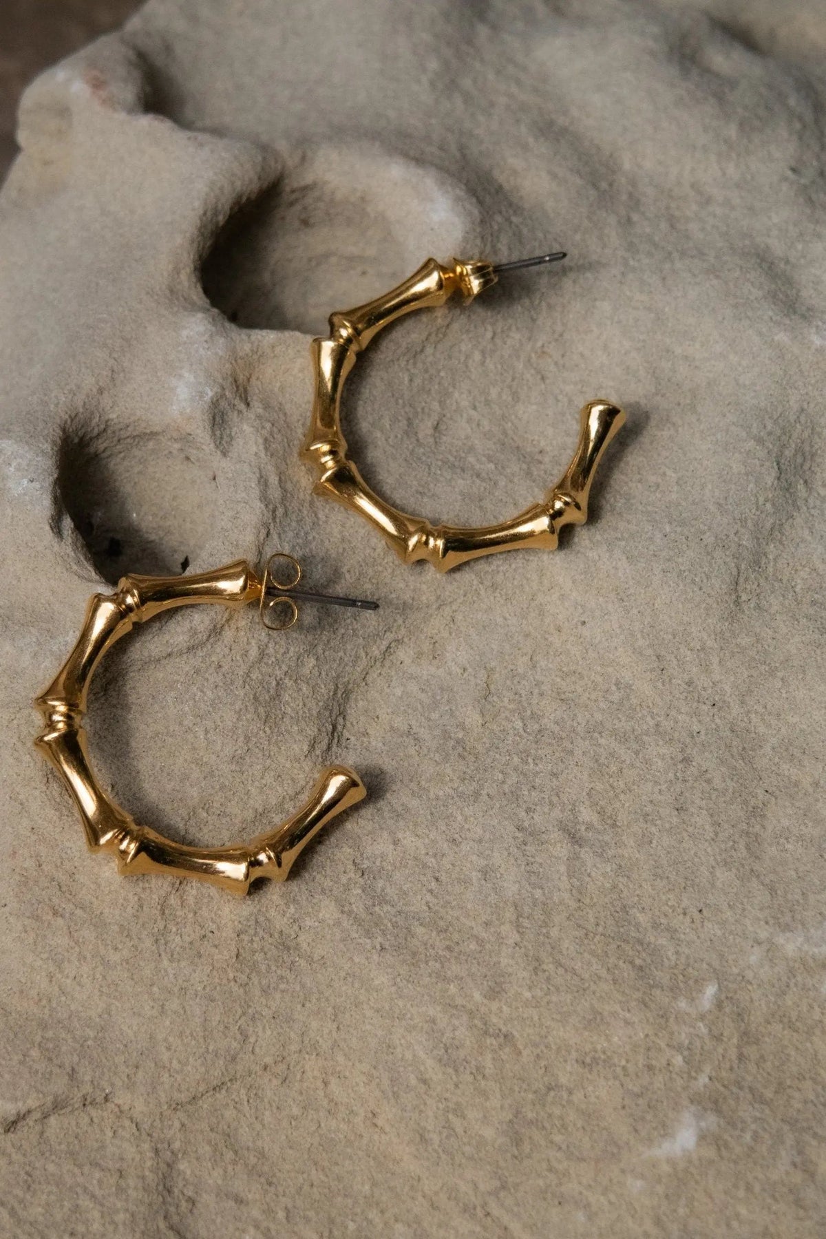 Gold hoop earrings in polished gold-tone metal, shaped like bamboo with segmented joints and post-back closures