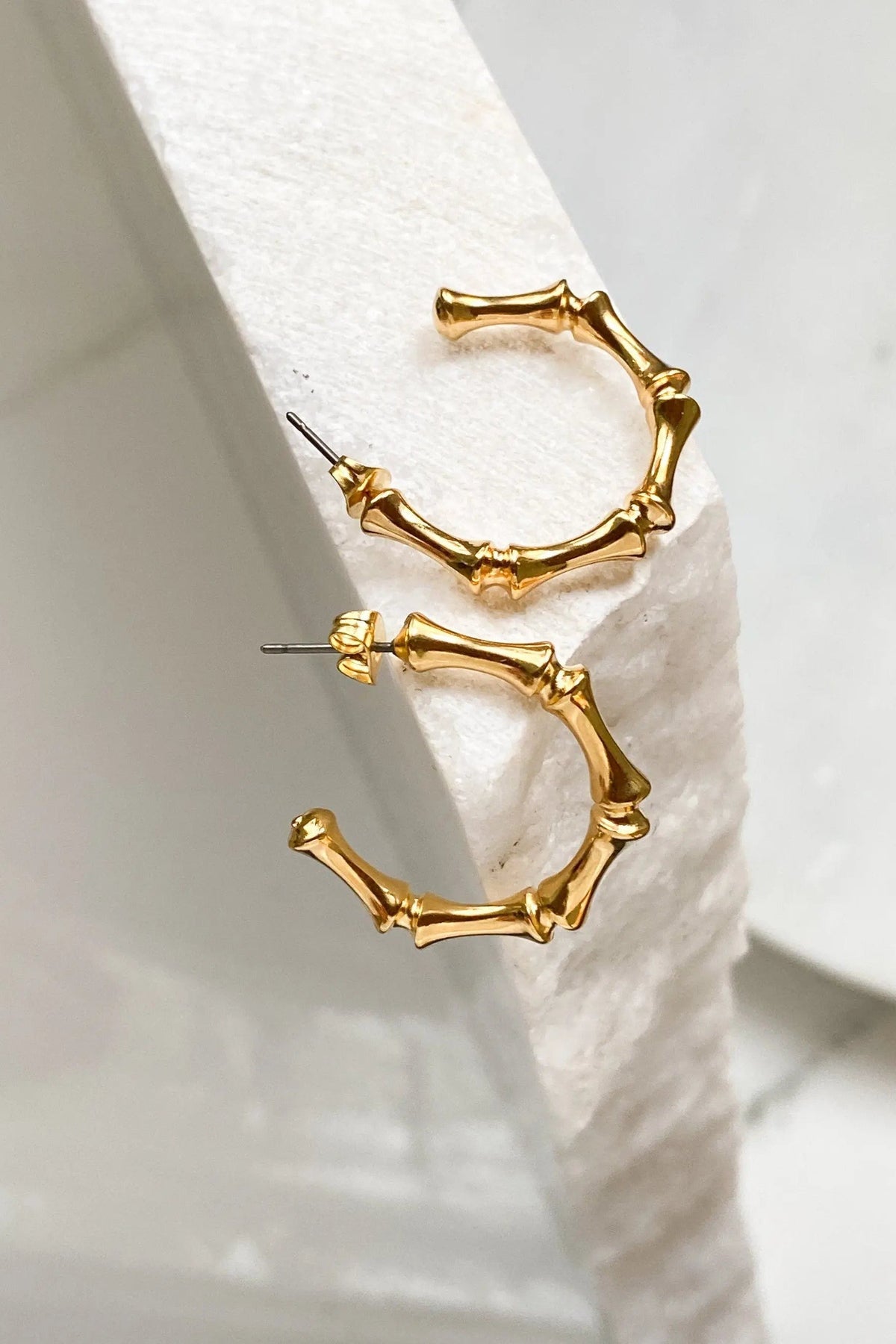 Gold hoop earrings in a polished gold-tone finish, featuring irregular segmented bamboo-like hoops and slim posts.