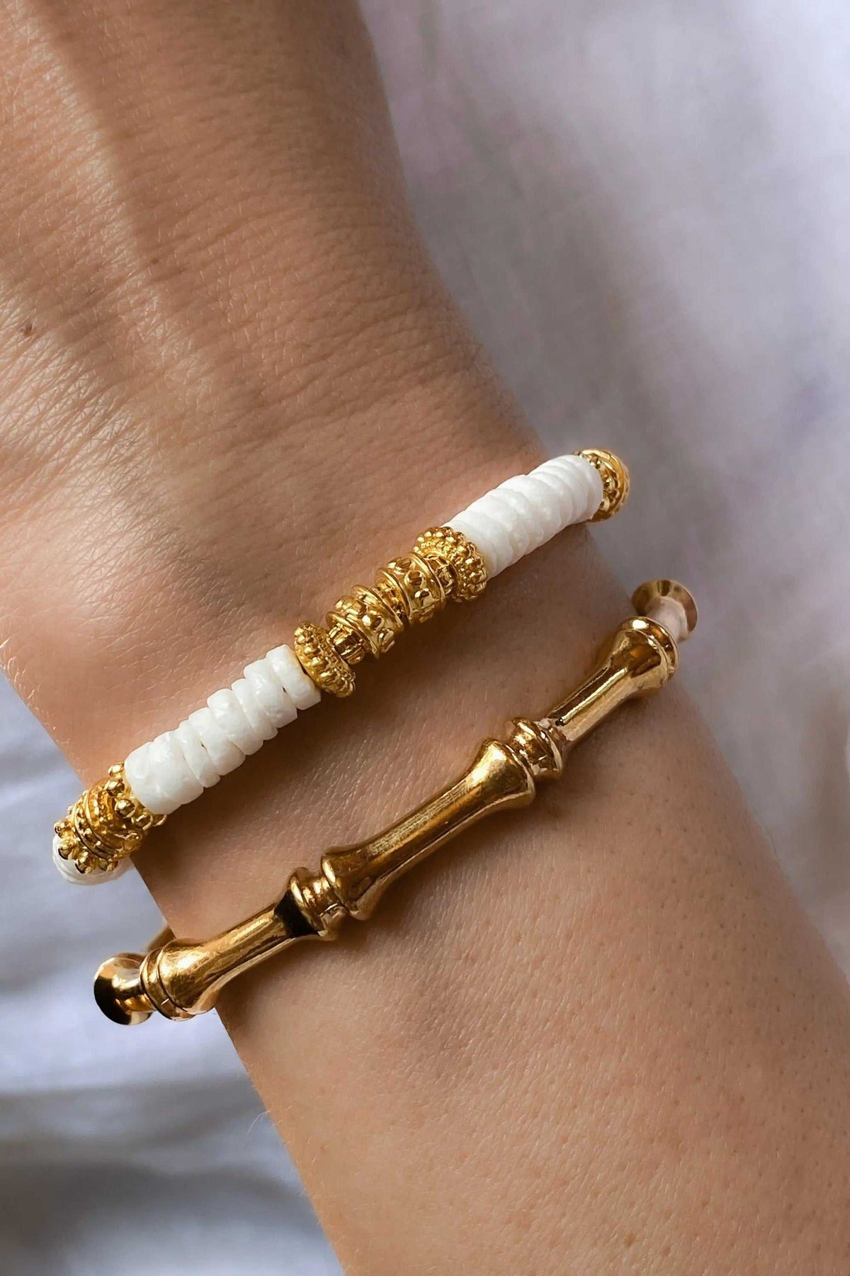 Gold hoop earrings with polished gold-tone bamboo-style hoops and white ribbed bead sections accented by ornate gold details
