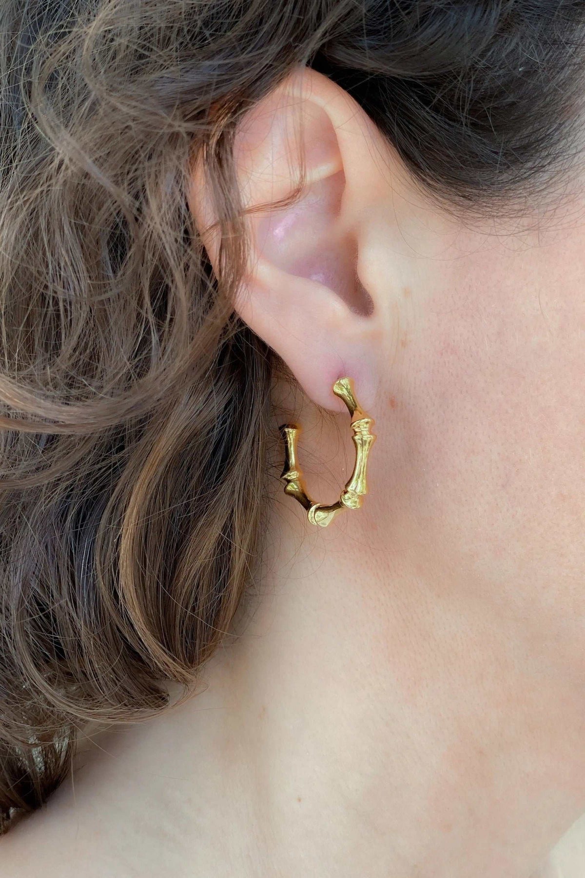 Gold hoop earrings with a polished yellow-gold finish, textured organic curves and small titanium post clasps.