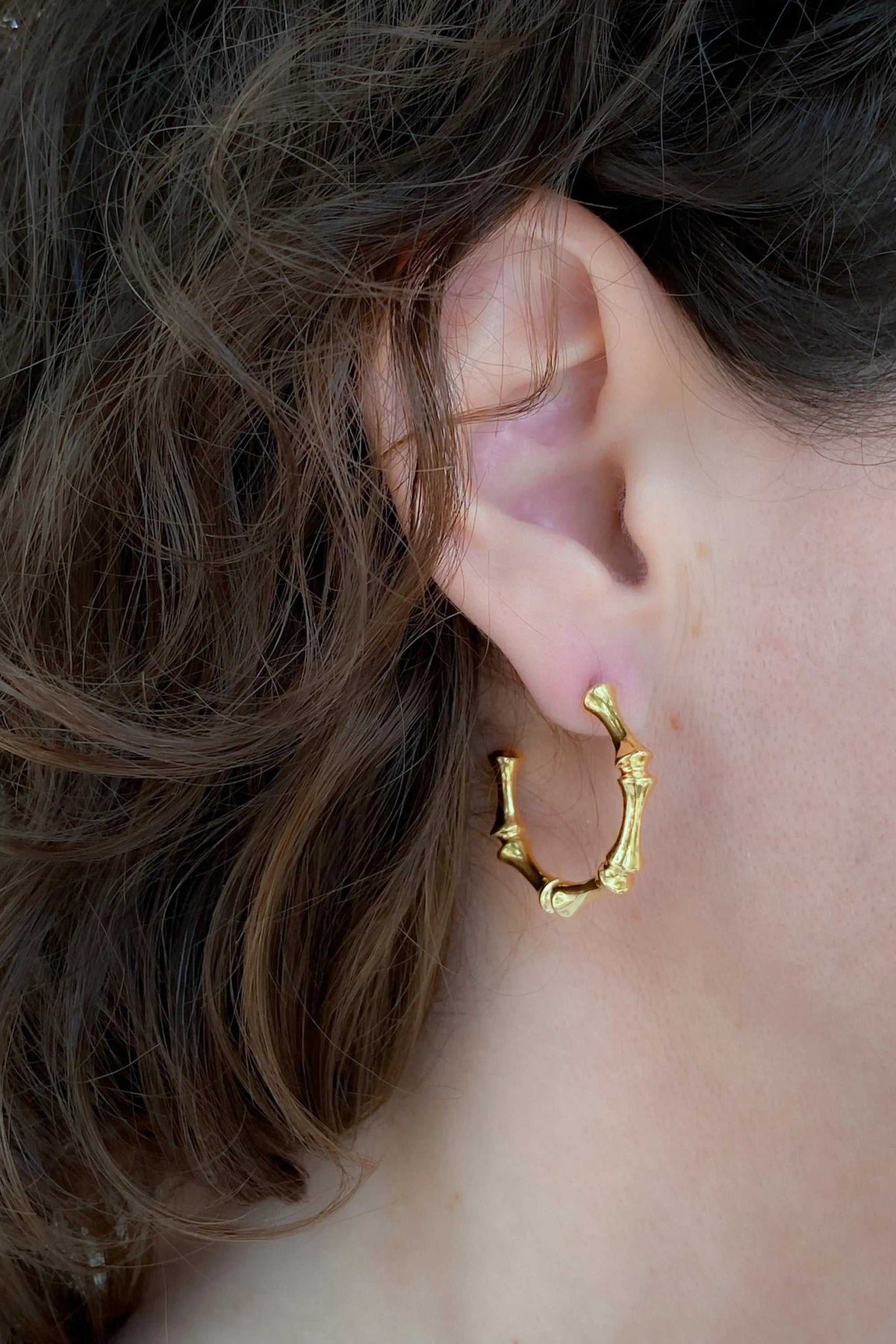 Gold hoop earrings with a polished gold finish, small sculptural organic details, and an open rounded shape