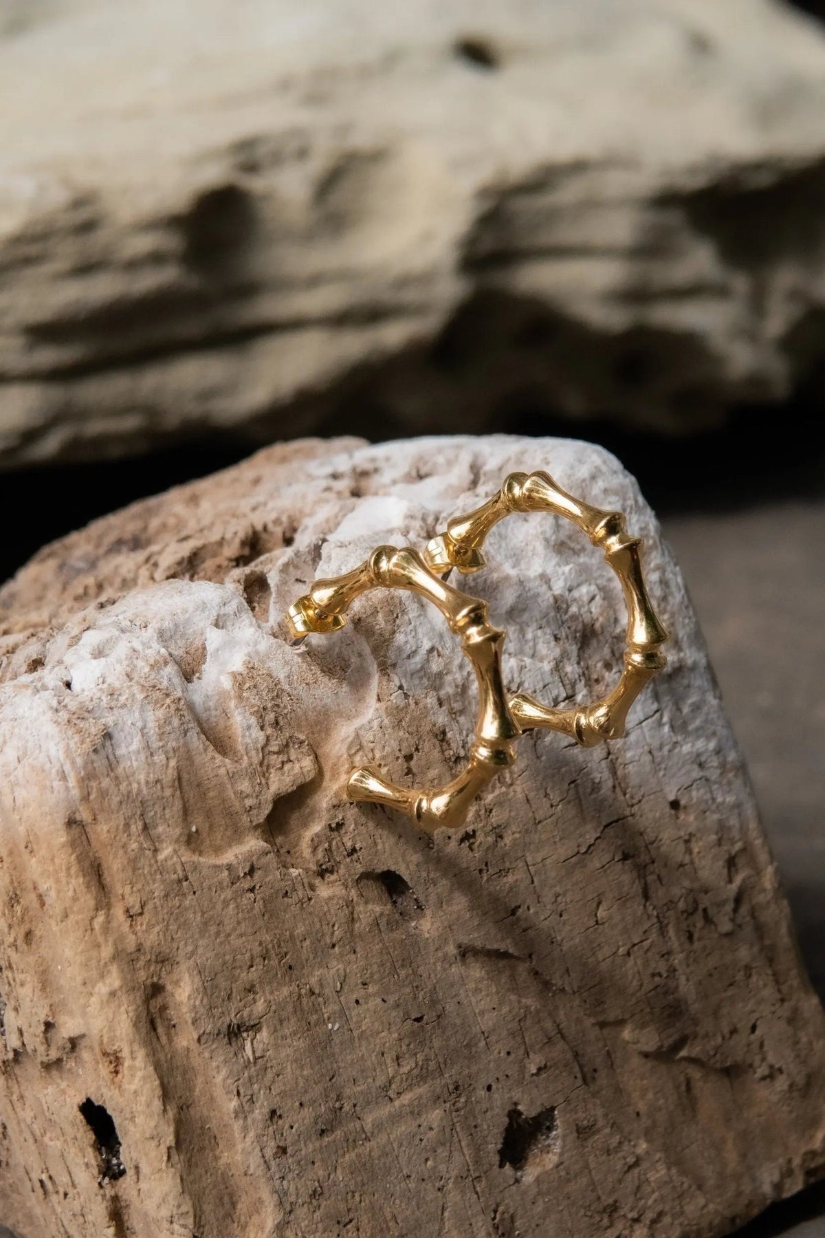 Gold hoop earrings with a polished gold finish and sculptural, irregular linked segments forming rounded hoops