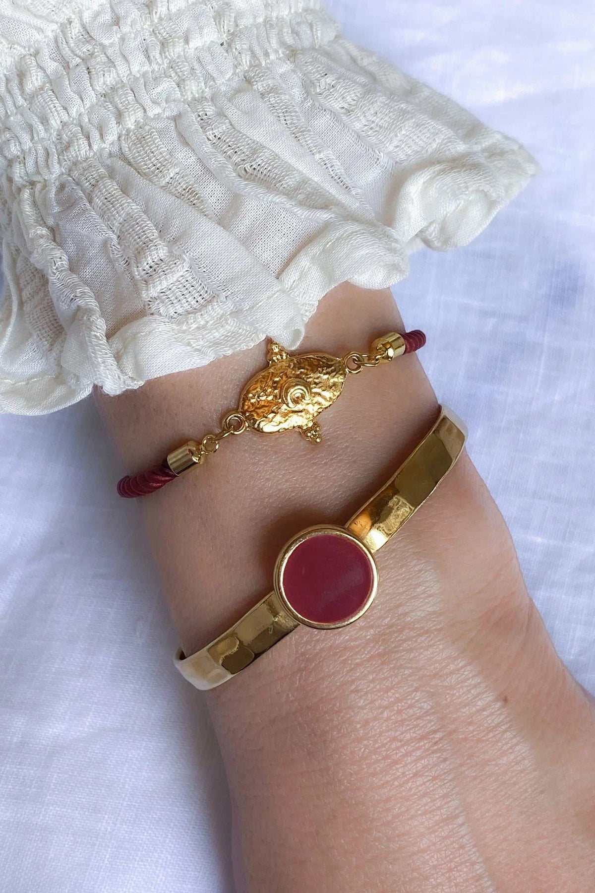 Gold plated Hammered bracelet in polished gold-tone metal with a round burgundy enamel centerpiece and hammered band