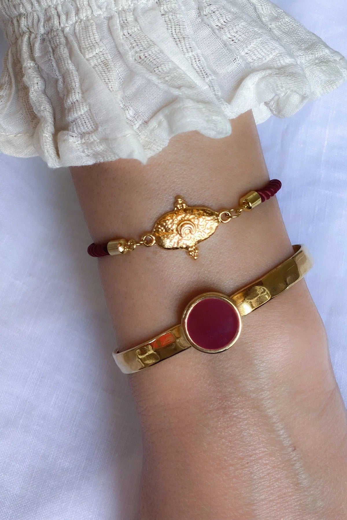 Gold plated Hammered bracelet with a wide polished gold-tone band and a round deep magenta enamel centerpiece