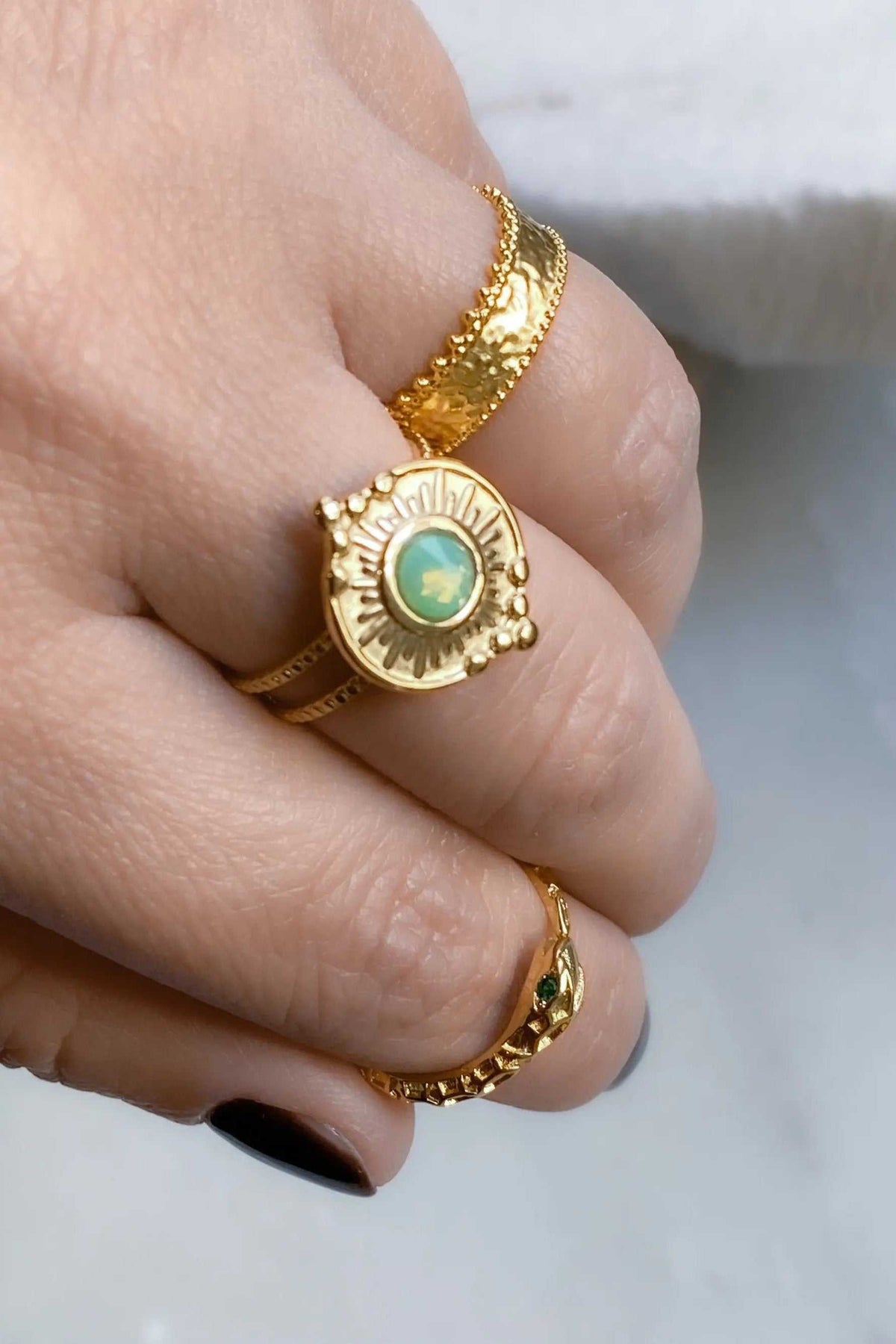 Gold Snake RING with a bright gold finish, textured serpent band and round green centerpiece stone