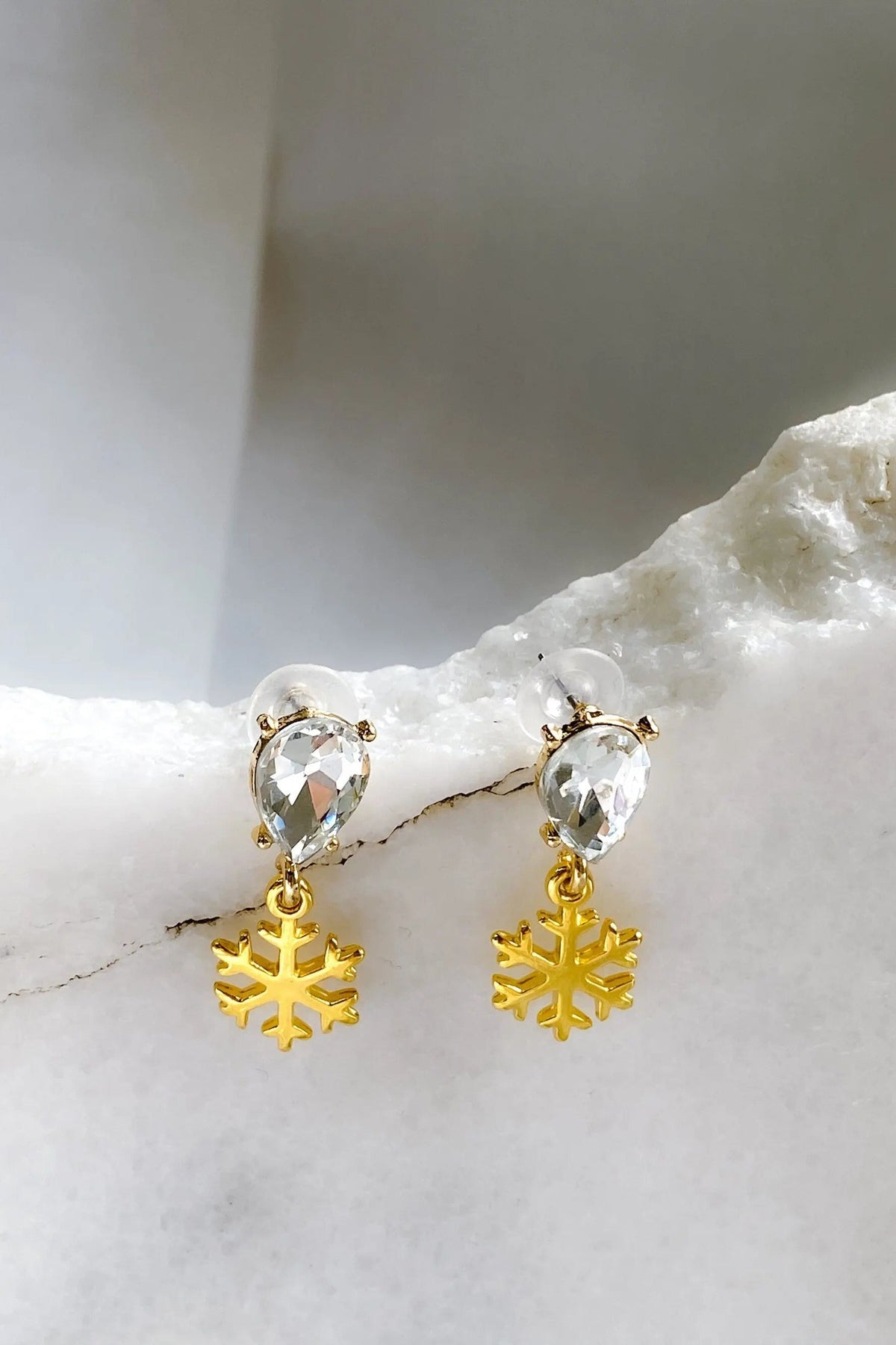Gold Snowflake Earrings with polished gold-tone snowflake charms and clear teardrop crystals in a dangling design