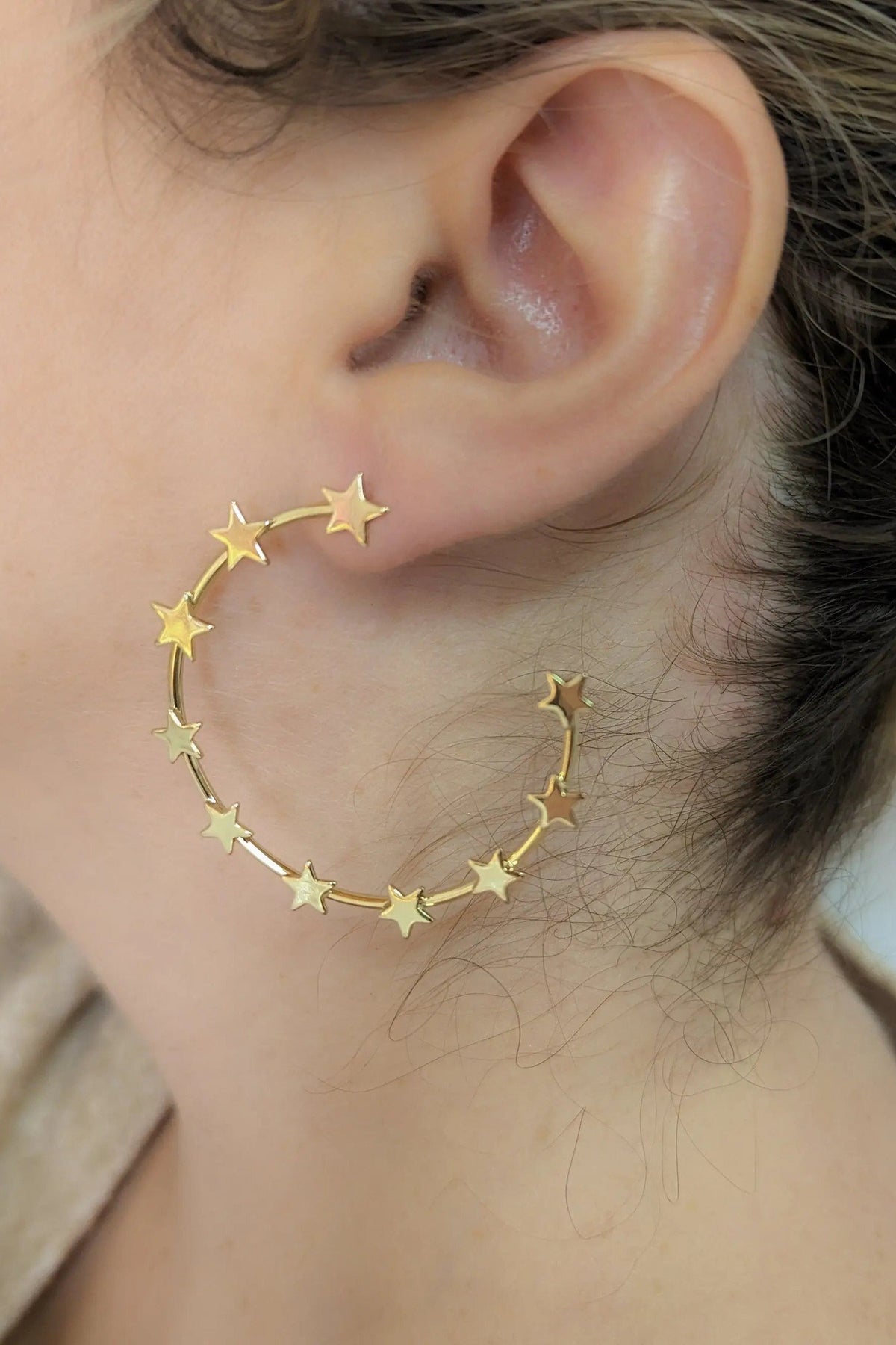 Gold Star Earring in gold-toned metal, featuring a large open hoop decorated with small star charms