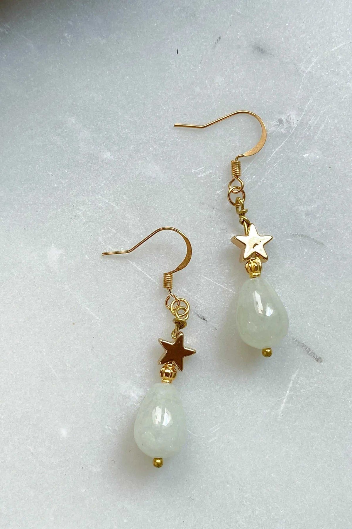 Gold star earrings with gold-tone star charms and pale green teardrop beads on hook wires