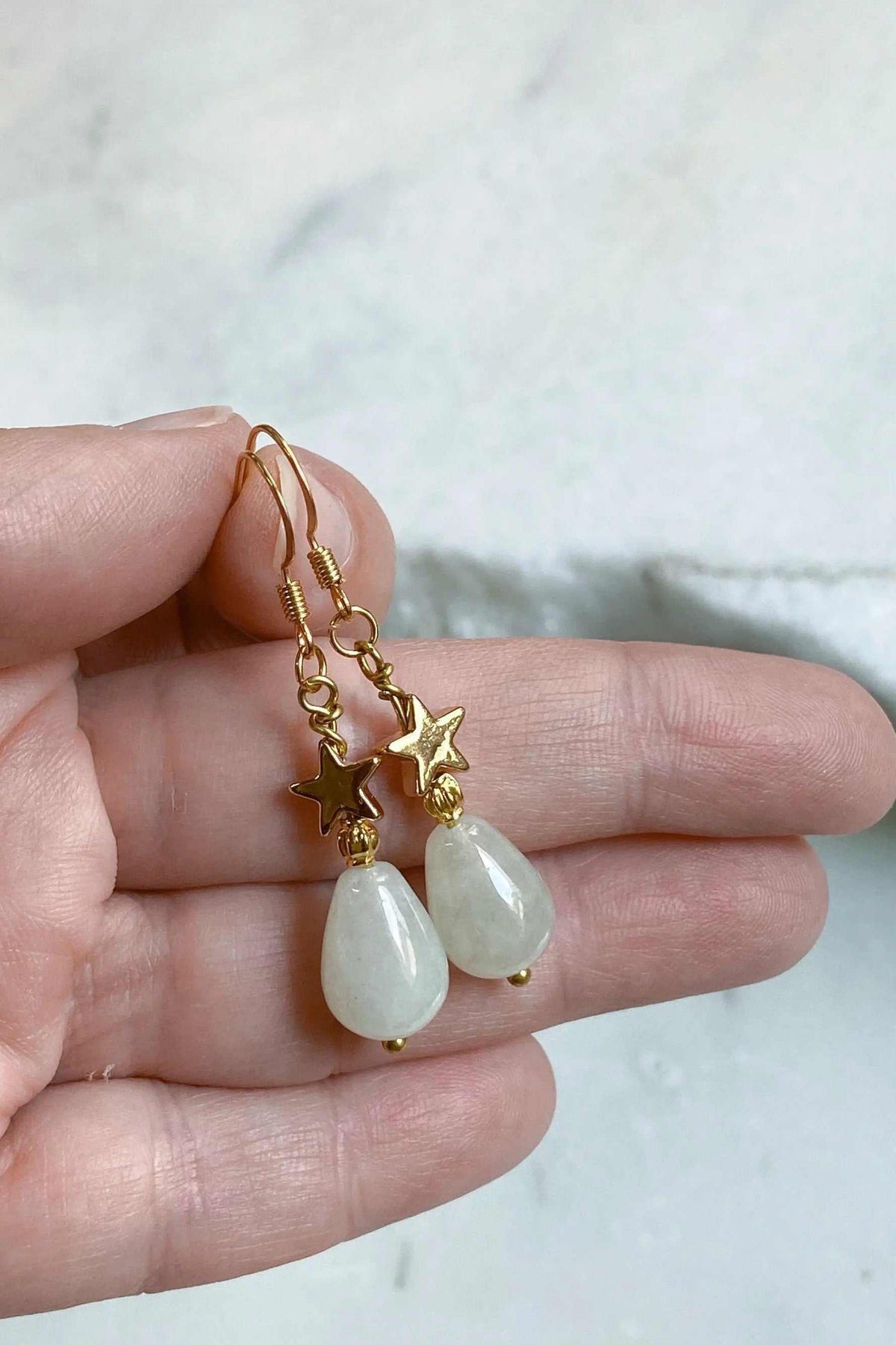 Gold star earrings with gold-tone star charms and pale green teardrop agate stones