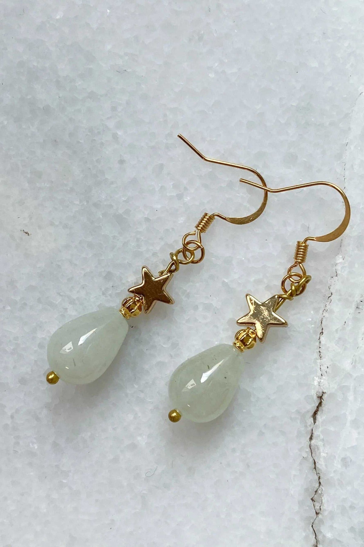 Gold star earrings with gold-toned star charms and pale green teardrop stones, dangling handmade design