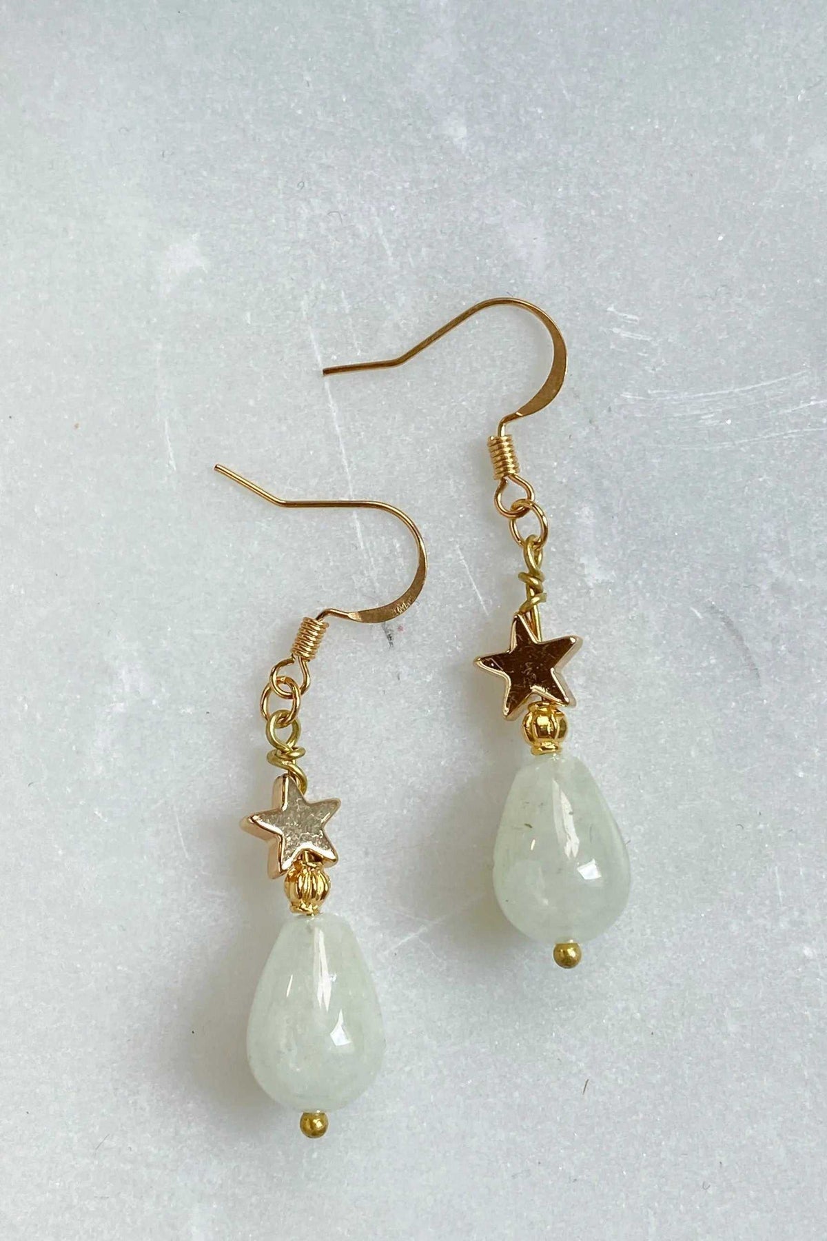 Gold star earrings with pale green teardrop beads, gold-toned star charms, and delicate dangling details