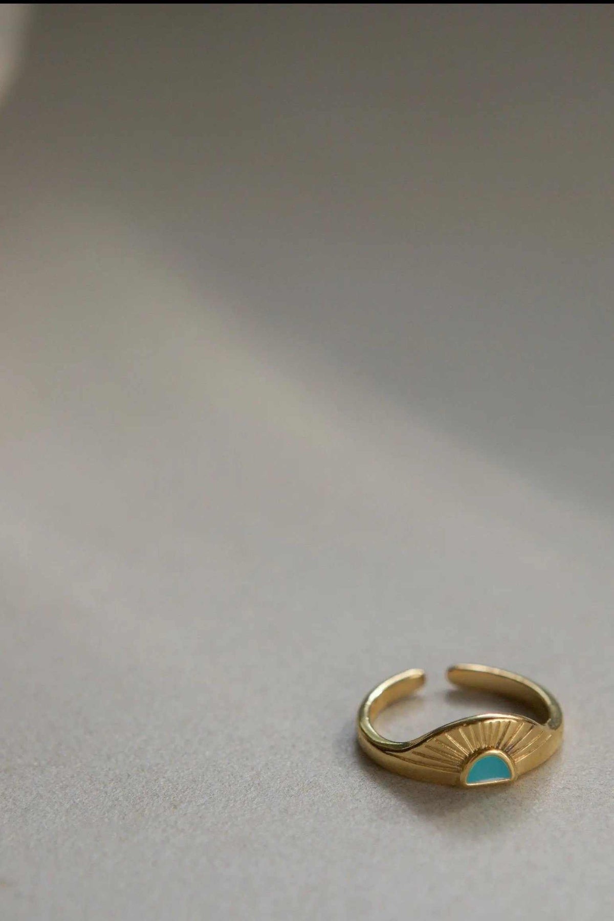 Greek ethnic boho ring in gold-tone metal with a sunburst fan detail and a small turquoise-colored stone, open adjustable band