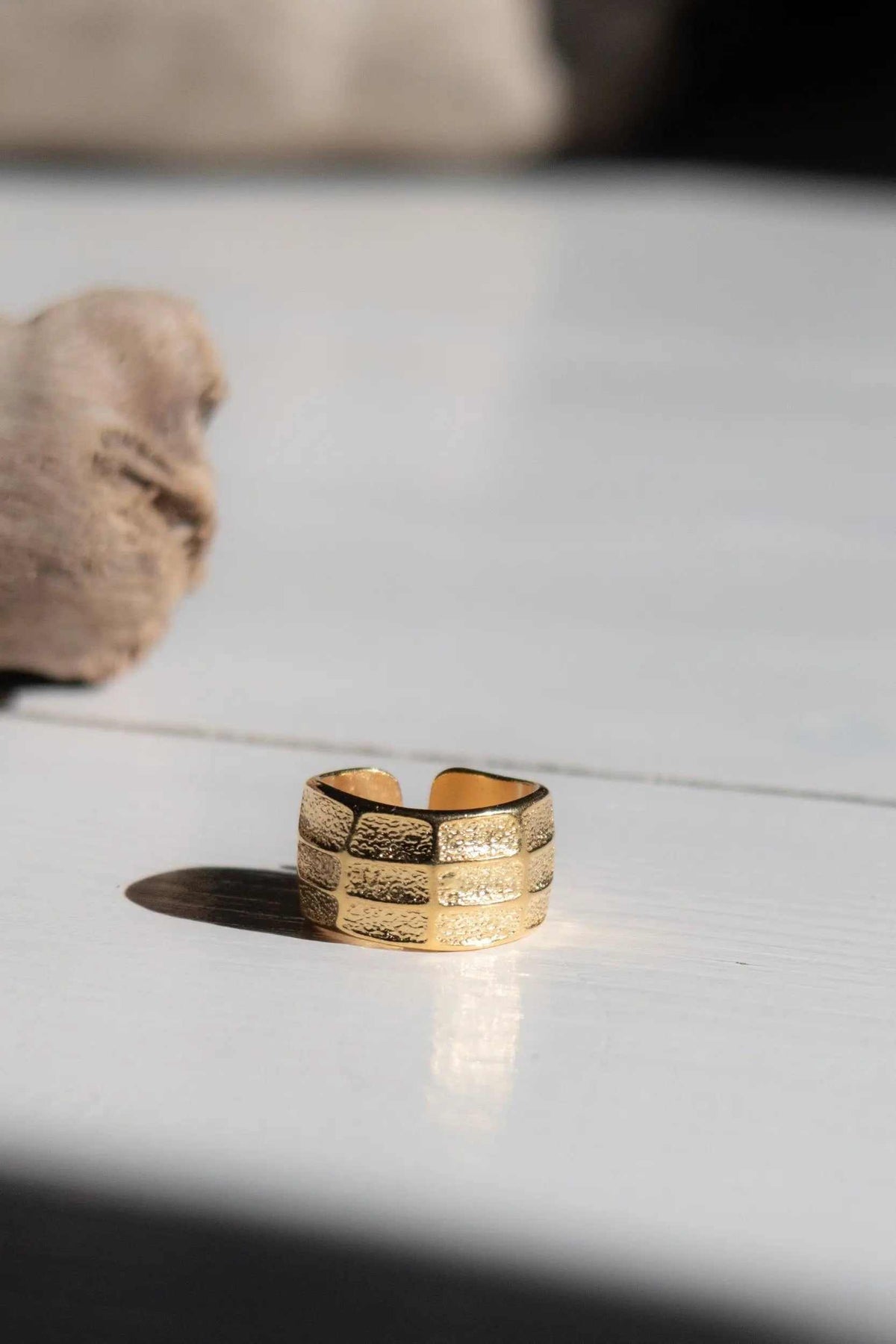 Greek wide ring in textured gold-tone metal, with a broad open adjustable band and engraved horizontal detailing
