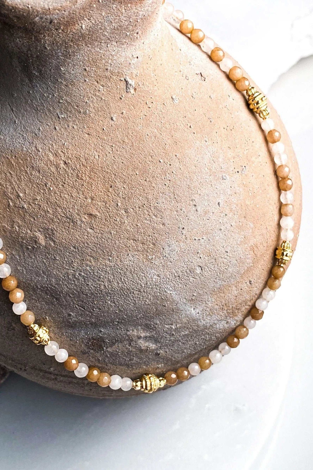 Heishi Bead Necklace with small round cream and honey-brown beads, accented by ornate gold-tone spacer beads