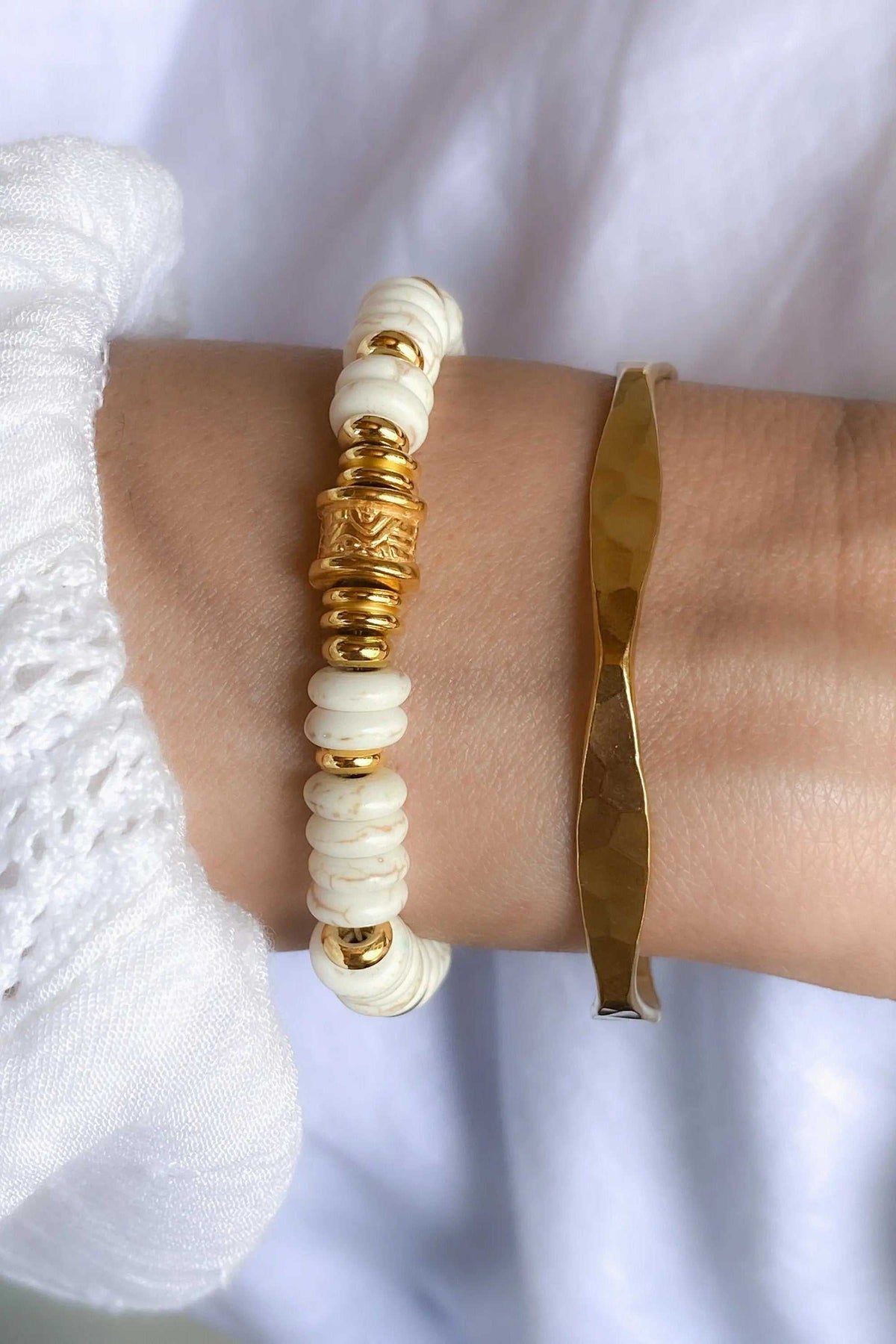 Heishi howlite beads bracelet with white disc-shaped beads and ornate gold-tone spacers, paired with a faceted gold cuff