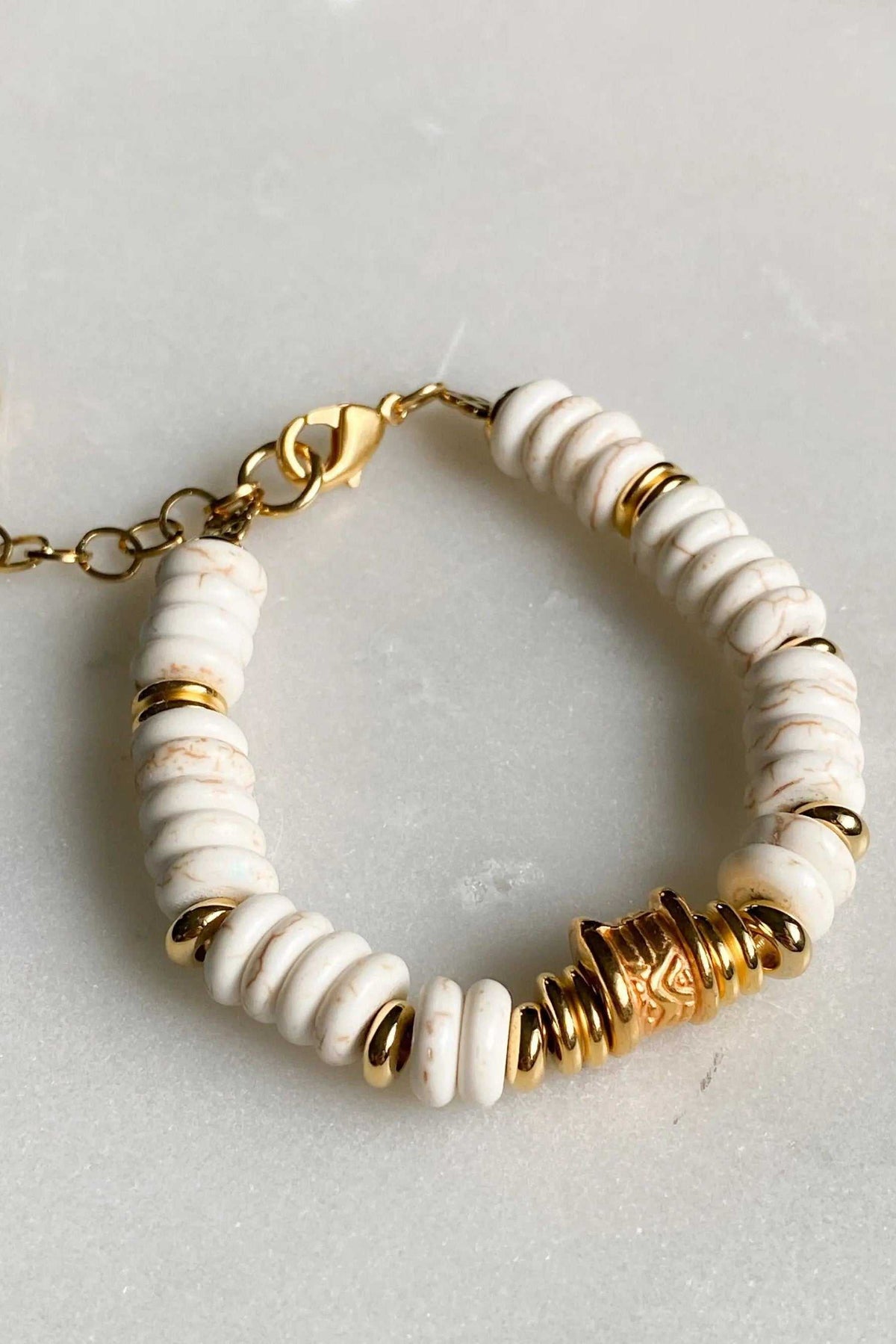 Bracelet with Heishi howlite beads in white with faint grey veining, accented by gold-tone spacer rings and sculptural details.