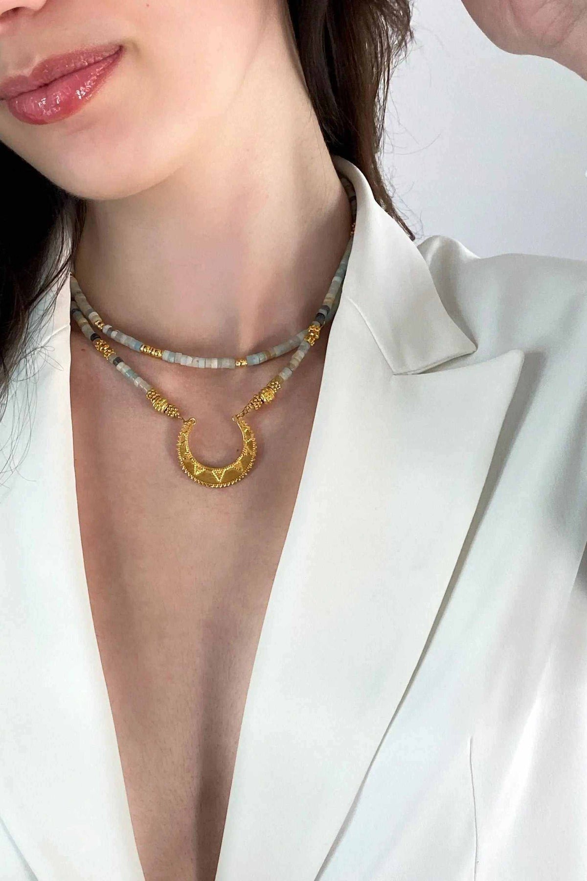 Heishi Necklace with pale blue and beige beads, gold details, and a large textured crescent pendant
