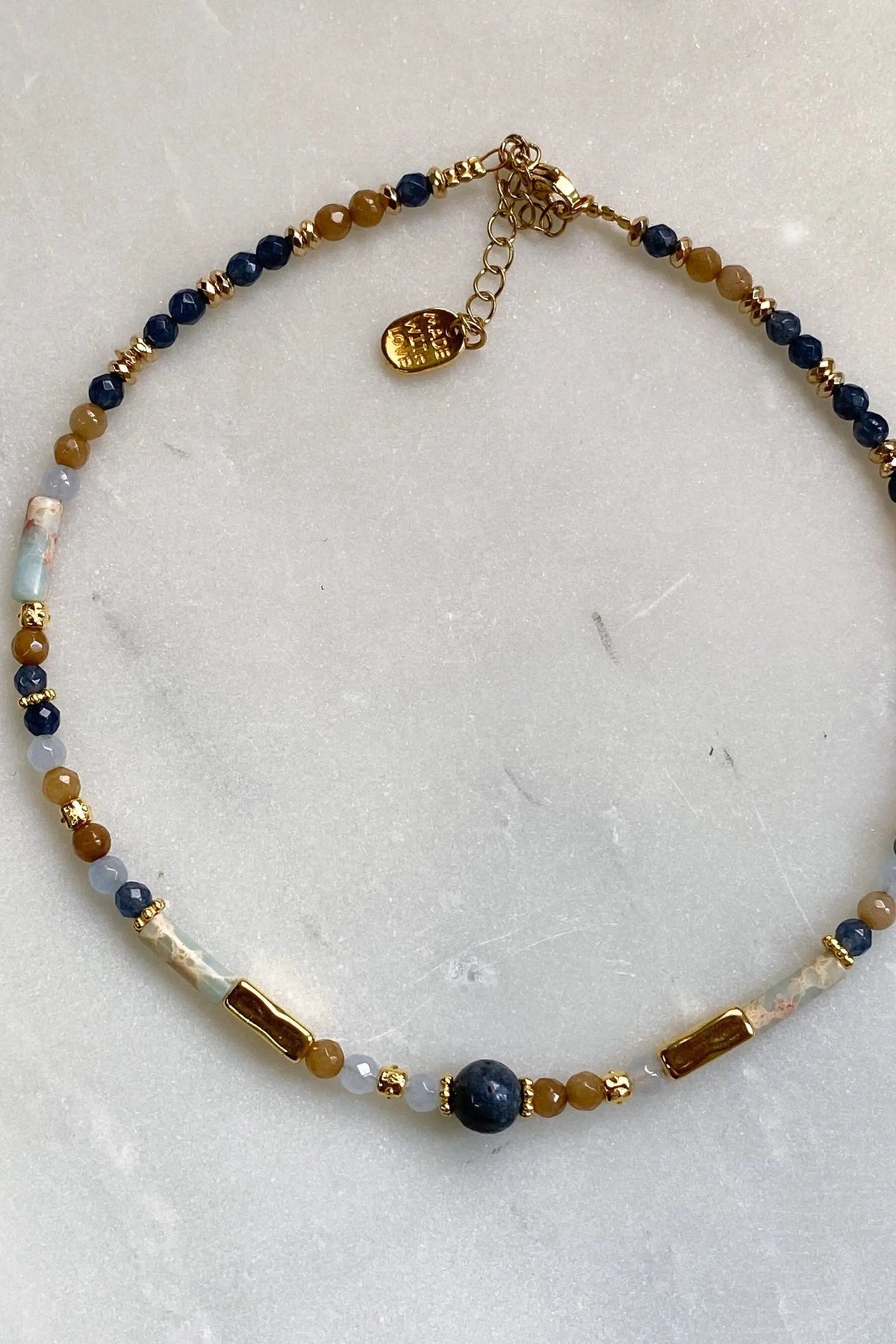Heishi Necklace with blue and brown beaded design, white shell accents, gold spacers and central dark blue bead