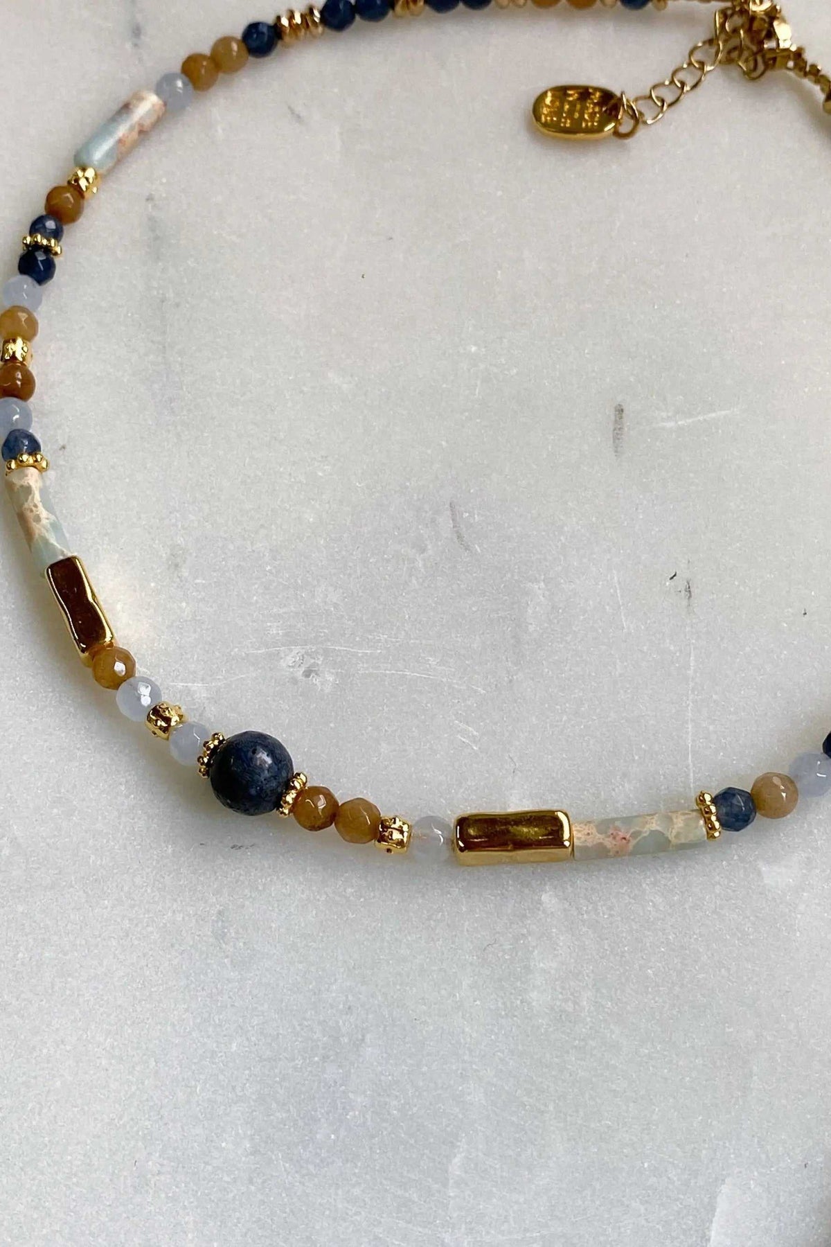 Heishi Necklace with blue, white and amber beads, shell-like pieces, gold accents and a statement charm