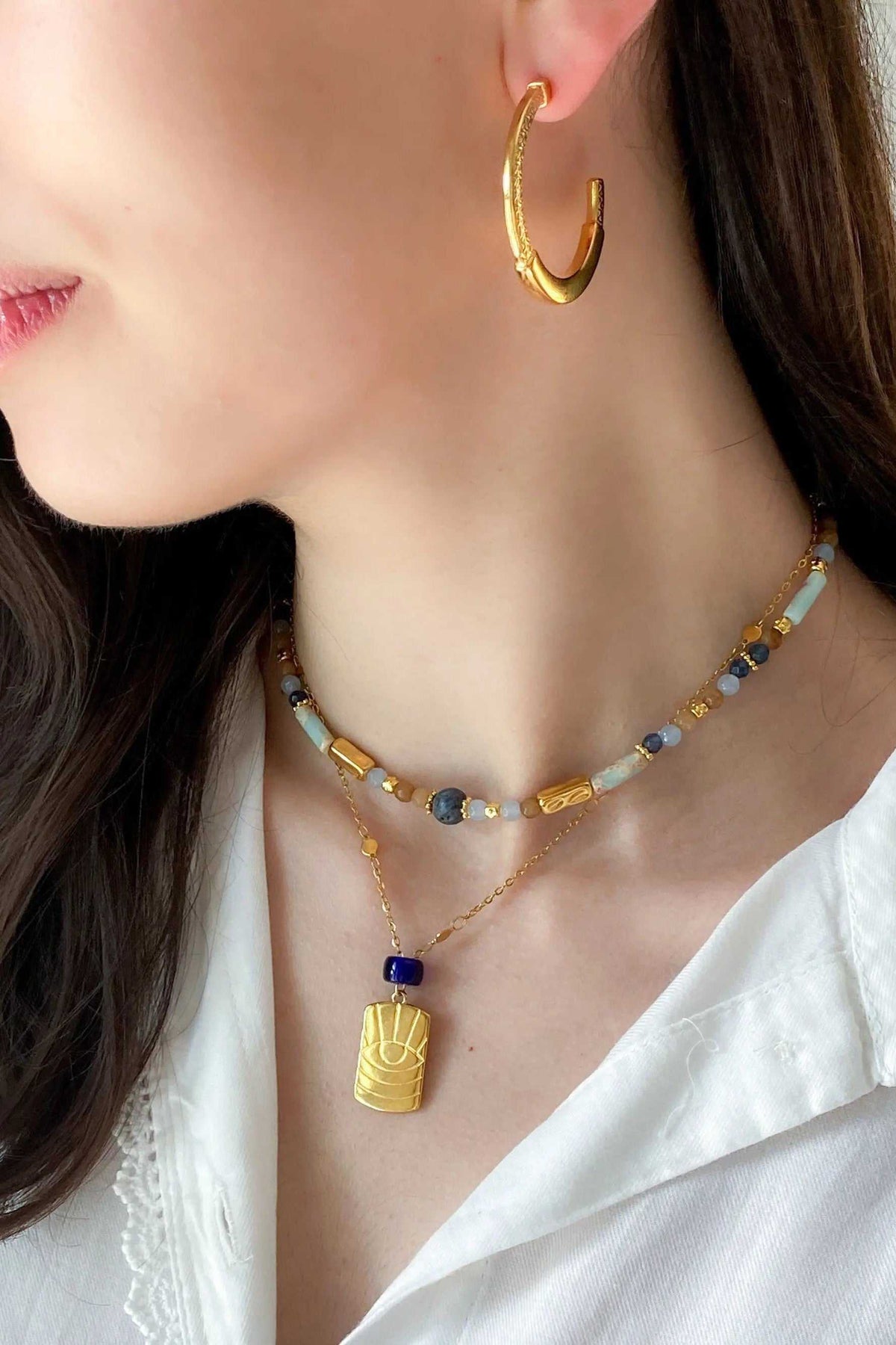 Heishi Necklace with blue and white beads, gold accents, and a pendant featuring a gold decorative charm