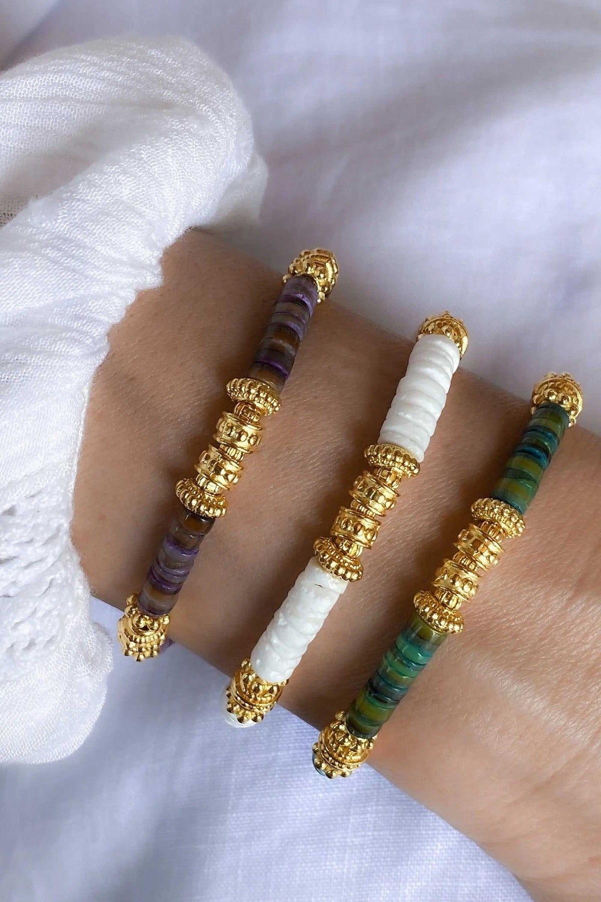 Heishi shell beads bracelet with white, purple, and green disc beads, gold-tone decorative spacers and end caps