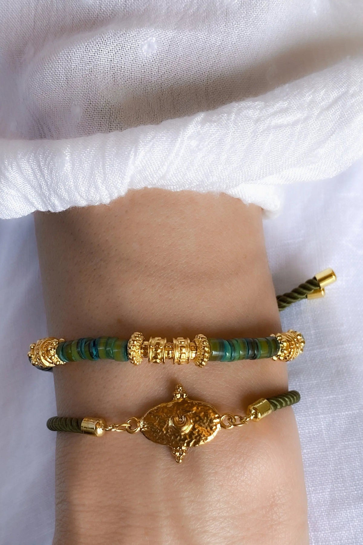 Heishi shell beads bracelet with dark green beads, gold plated accents and an ornate central medallion