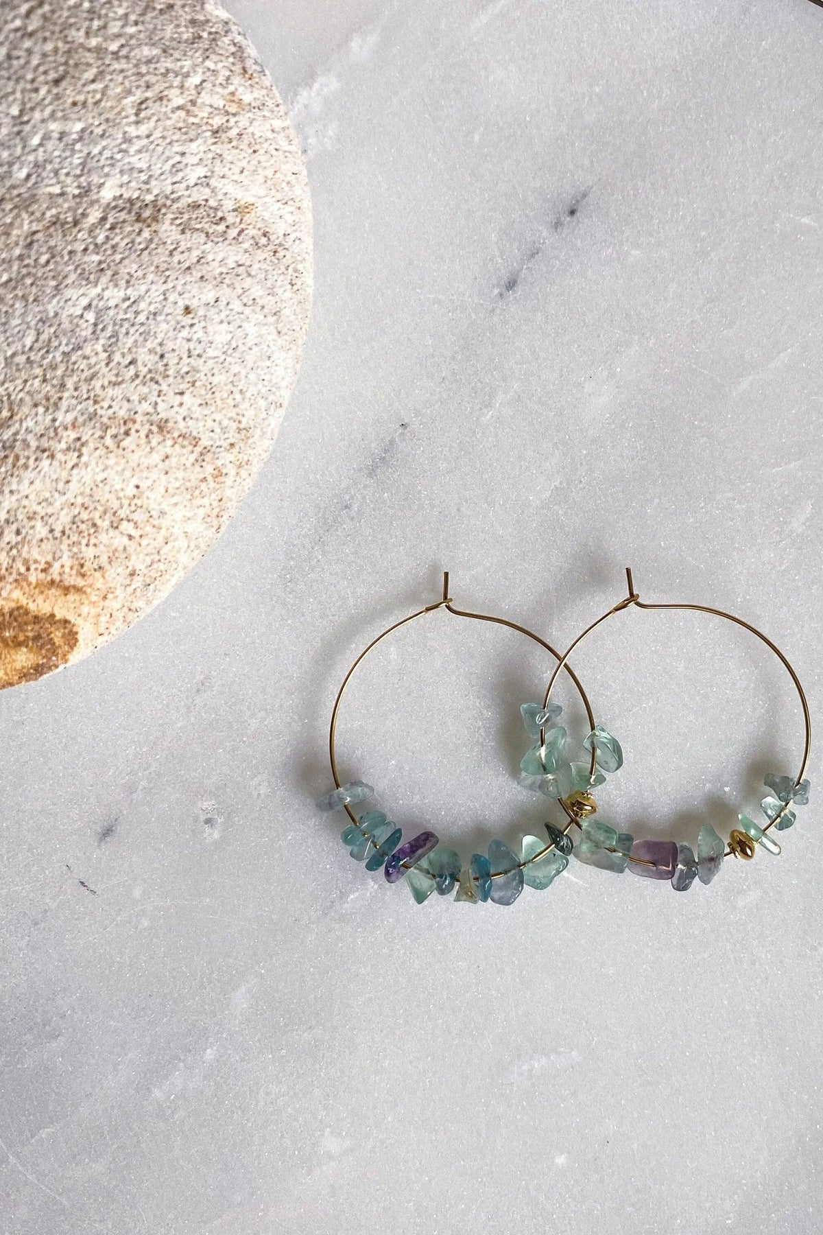 Hoop crystal earrings with gold-tone wire hoops and translucent blue-green crystal chips accented by purple stones