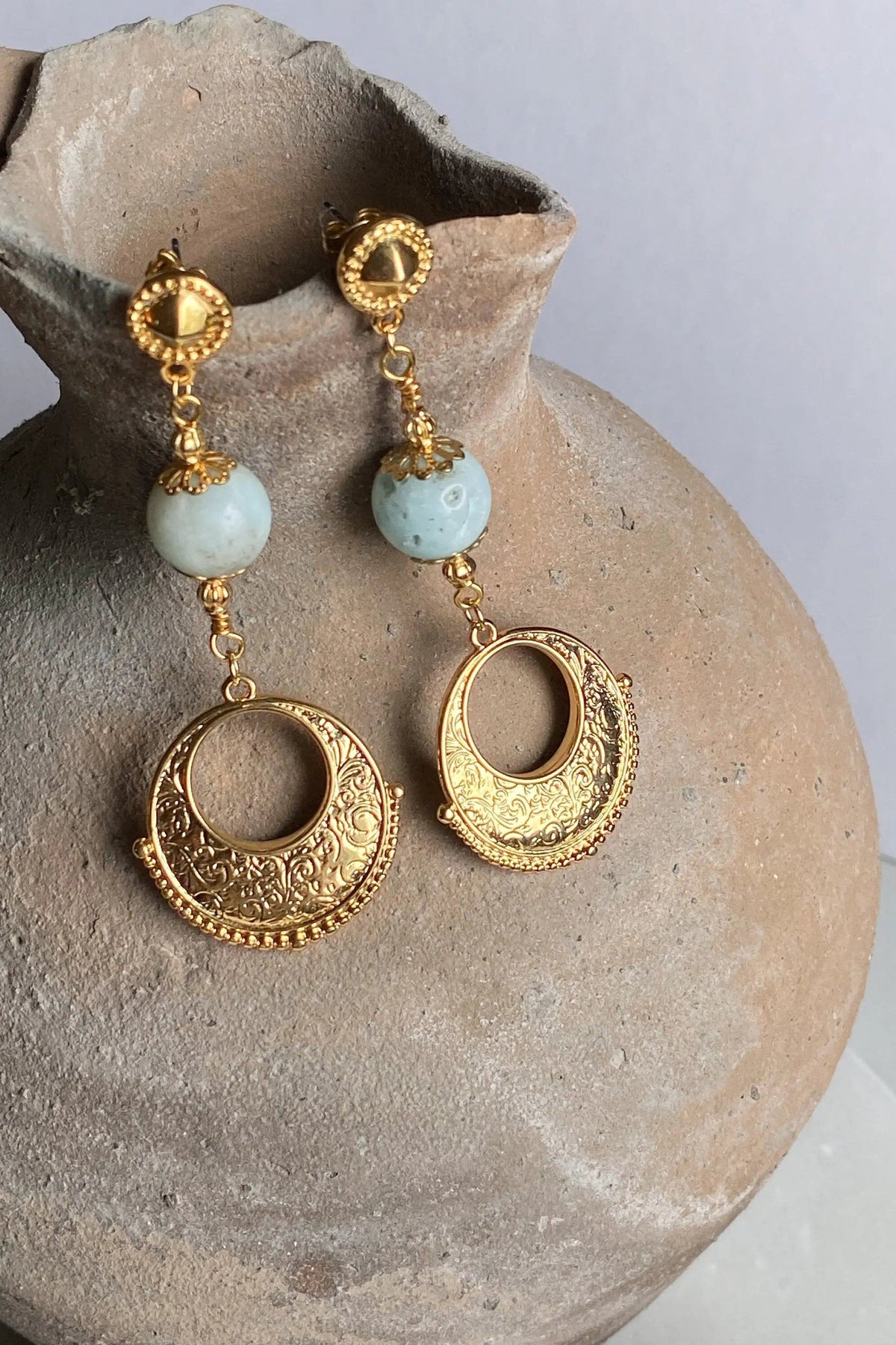 IRIS Amazonite Earrings feature pale blue round stones and ornate gold-tone circular drops with textured details.
