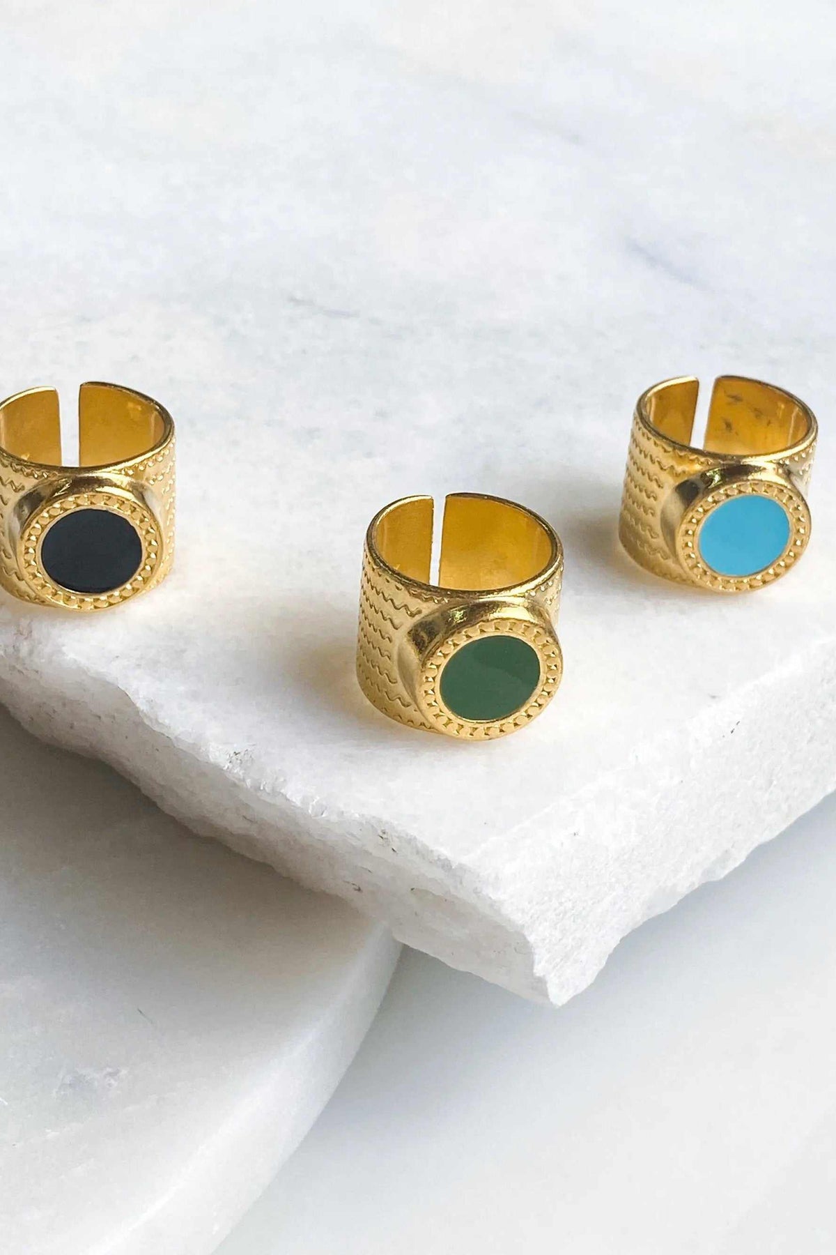 KARMI Gold wide band ring in textured gold tone, shown in three colours with black, green and turquoise oval stones.
