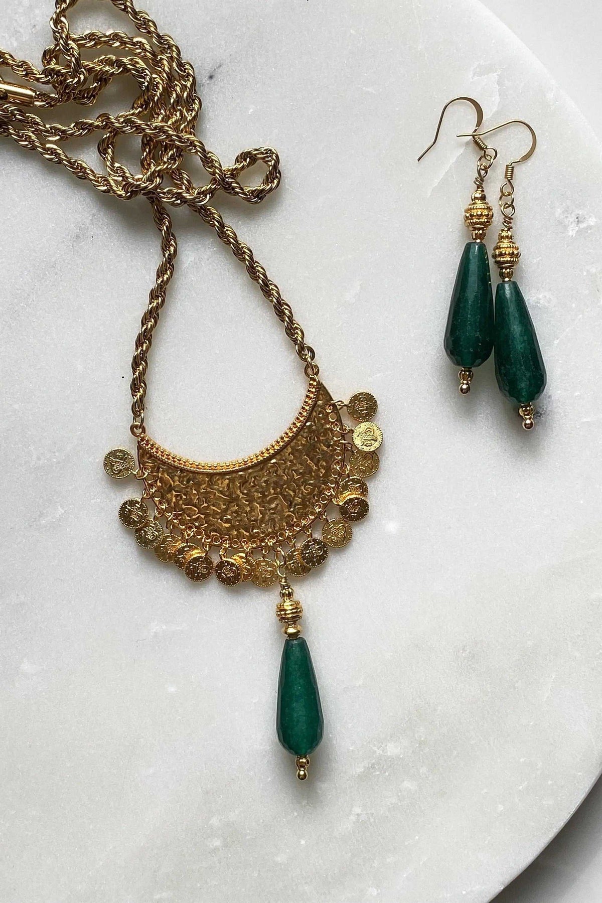 KIVÉLI Boho Necklace with ornate gold-tone pendant, textured chain, and dark green teardrop gemstone