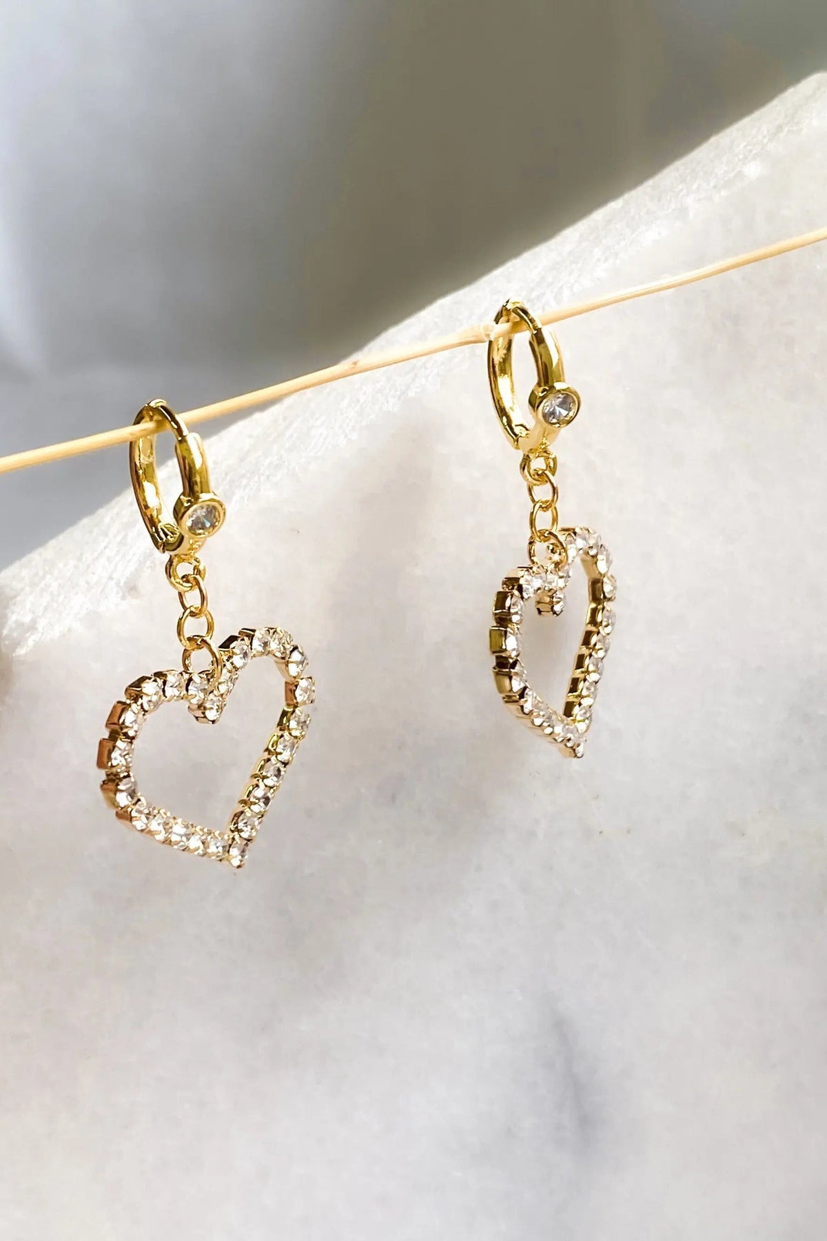 Large Heart Earrings in gold-tone metal feature dangling open heart charms edged with sparkling clear crystals.