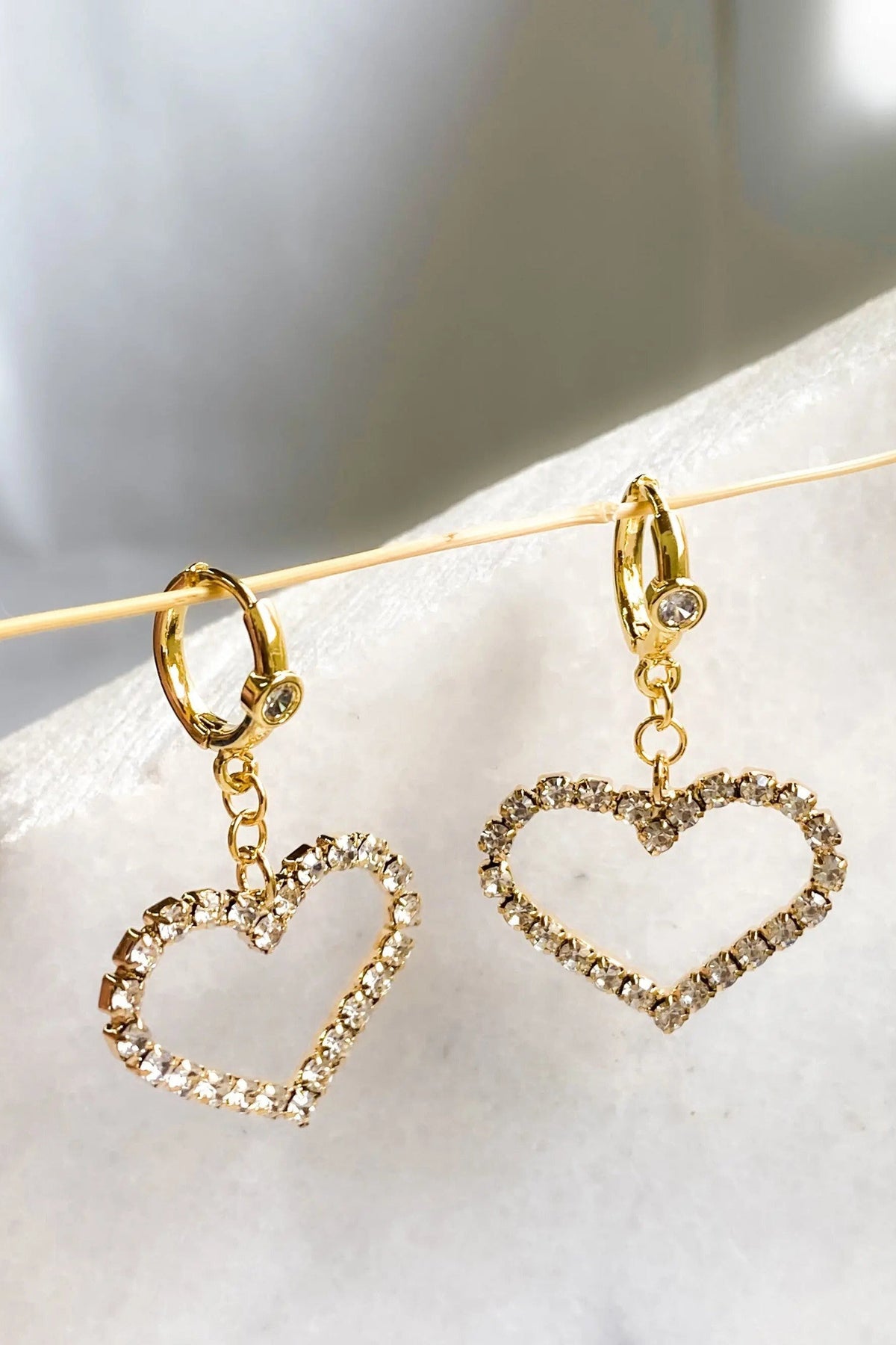 Large Heart Earrings in gold-tone metal feature huggie hoops and open heart charms edged with sparkling clear crystals.