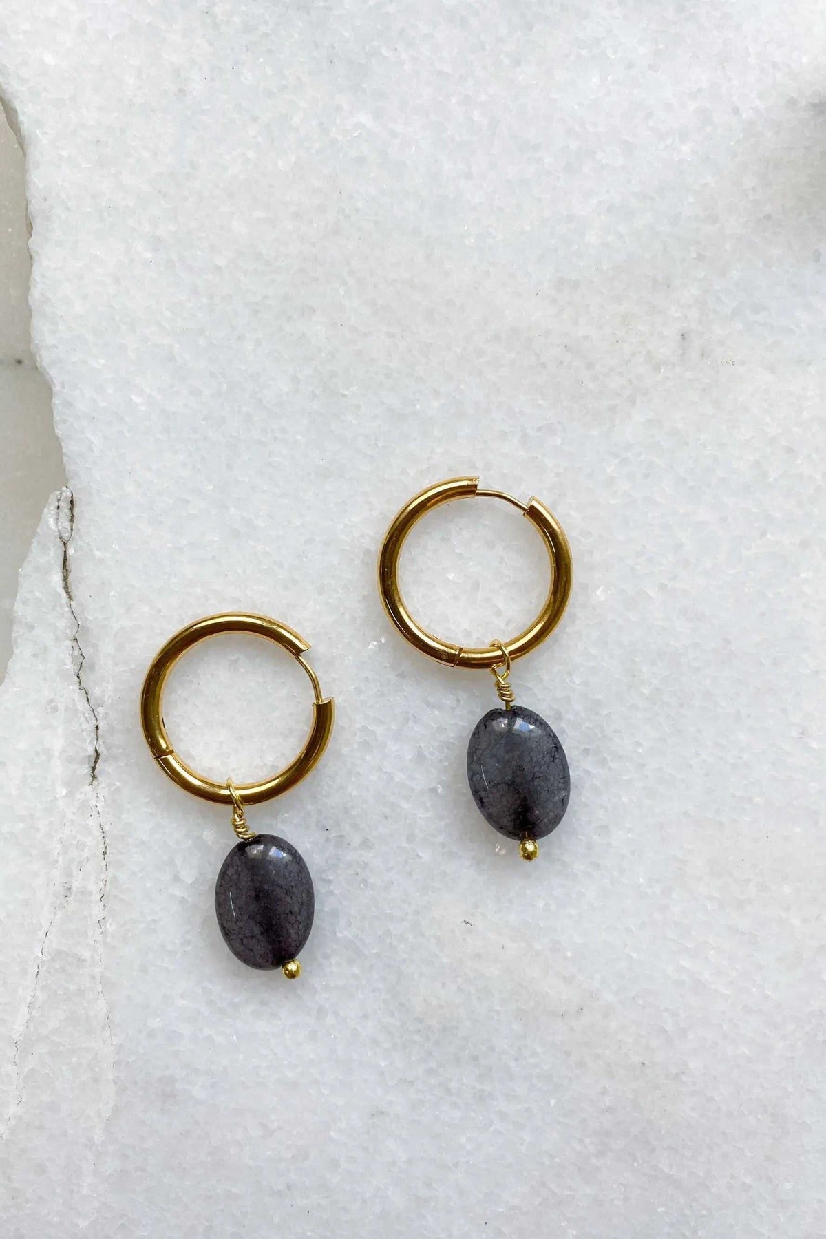 Large hoop earrings in gold-toned metal with dark oval stone charms and small gold bead details