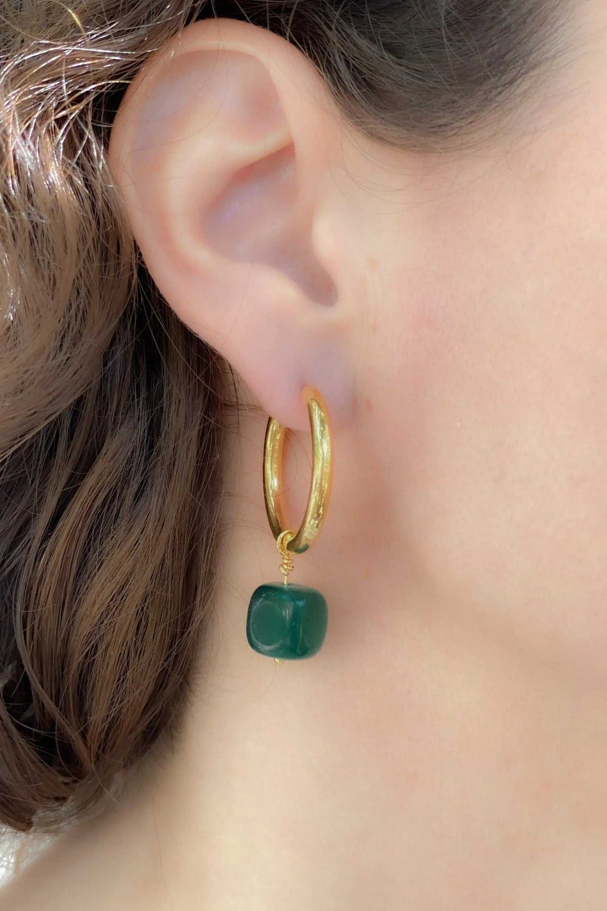 Large hoop earrings in gold-tone metal with a polished green stone charm and smooth hoop design
