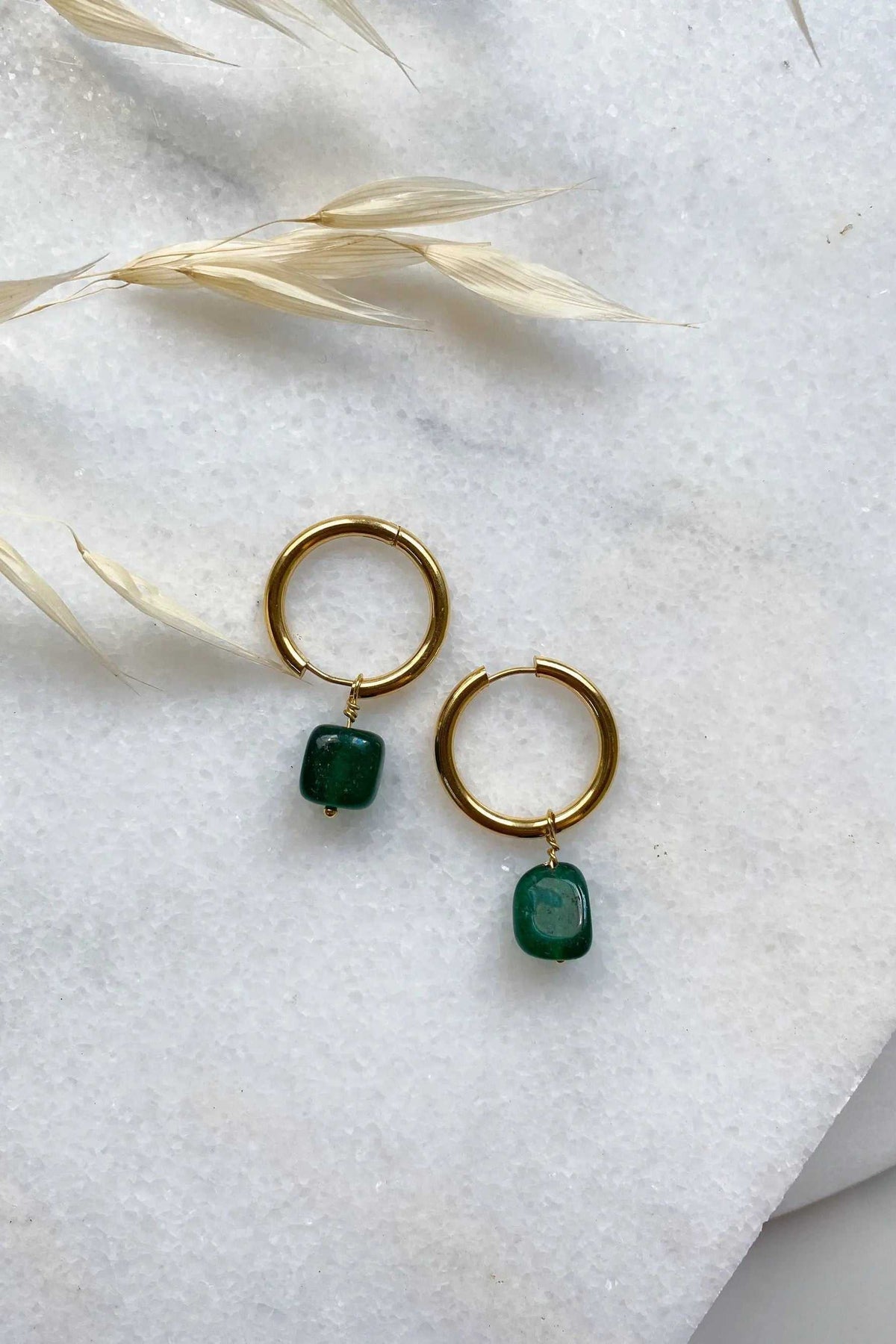 Large hoop earrings in gold-toned metal with matching dark green rounded stone charms