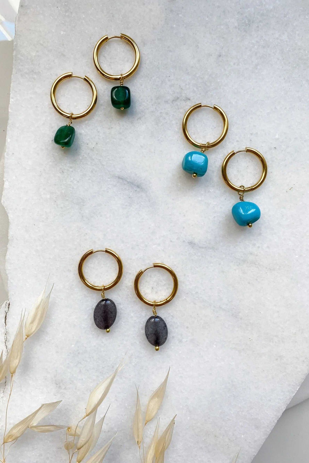 Large hoop earrings in gold-tone metal with green, turquoise, and dark stone charms