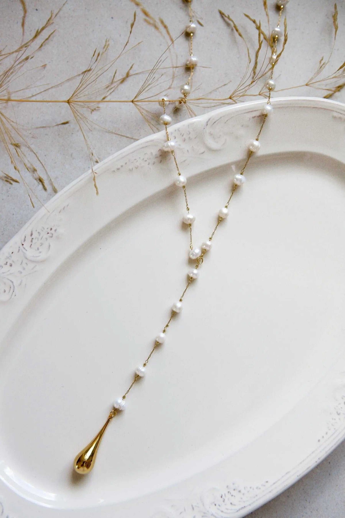 Lariat pearl necklace with gold-toned chain, white pearls, and a long teardrop pendant