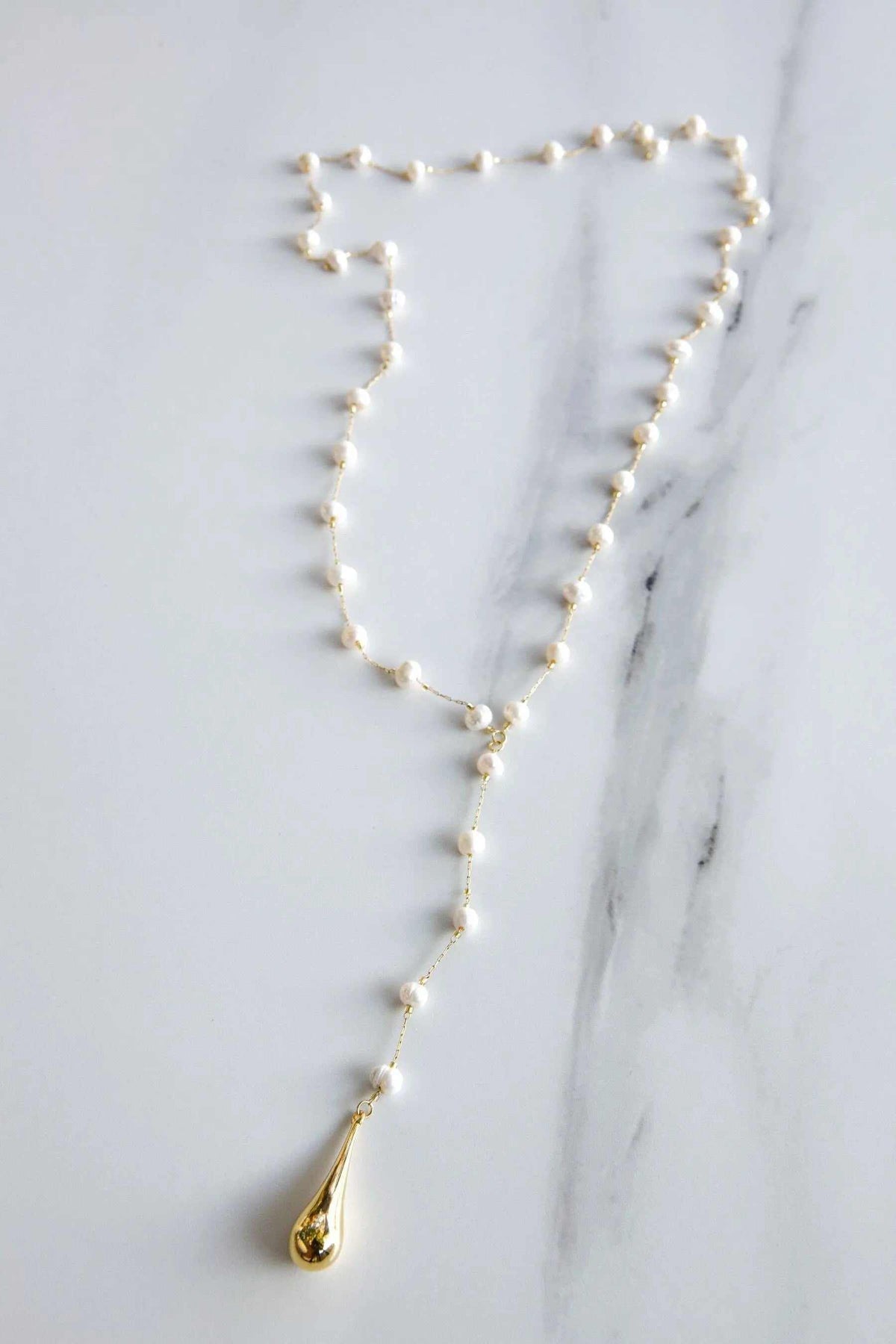 Lariat pearl necklace with a delicate gold-tone chain, white pearls, and a teardrop pendant