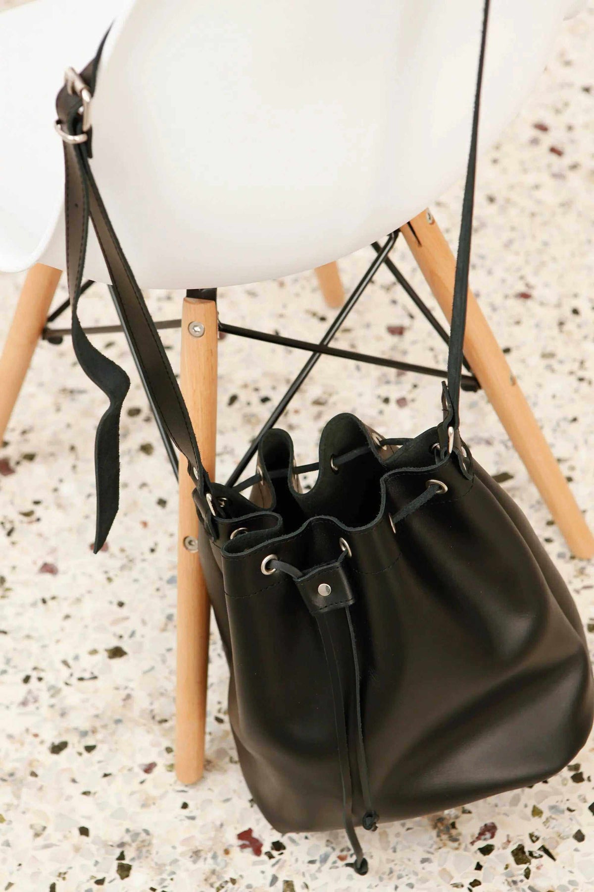leather women's handbag in dark brown leather with a soft bucket shape, drawstring top, and adjustable shoulder strap