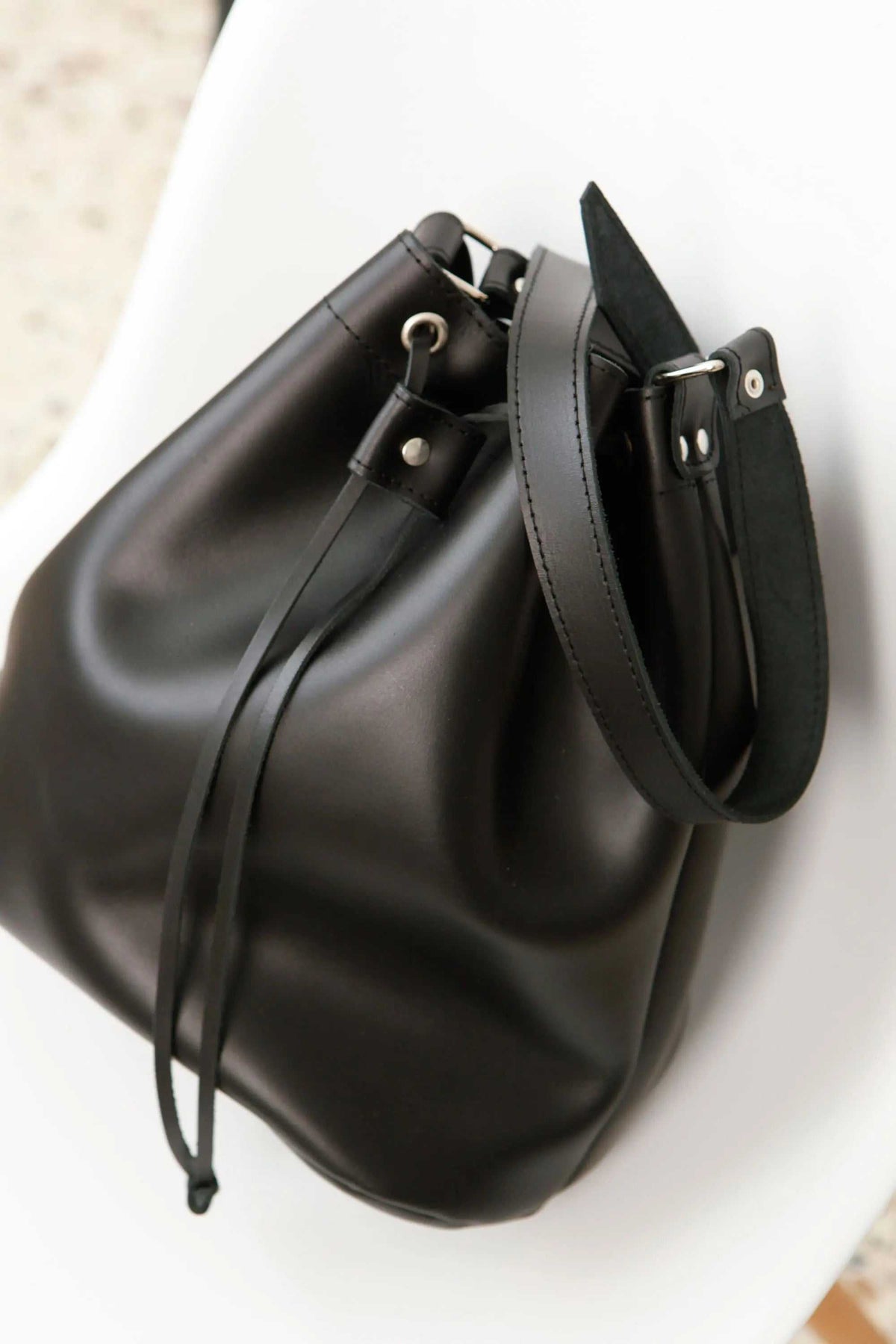 leather women's handbag in smooth black leather with a relaxed bucket shape, drawstring closure and wide adjustable strap