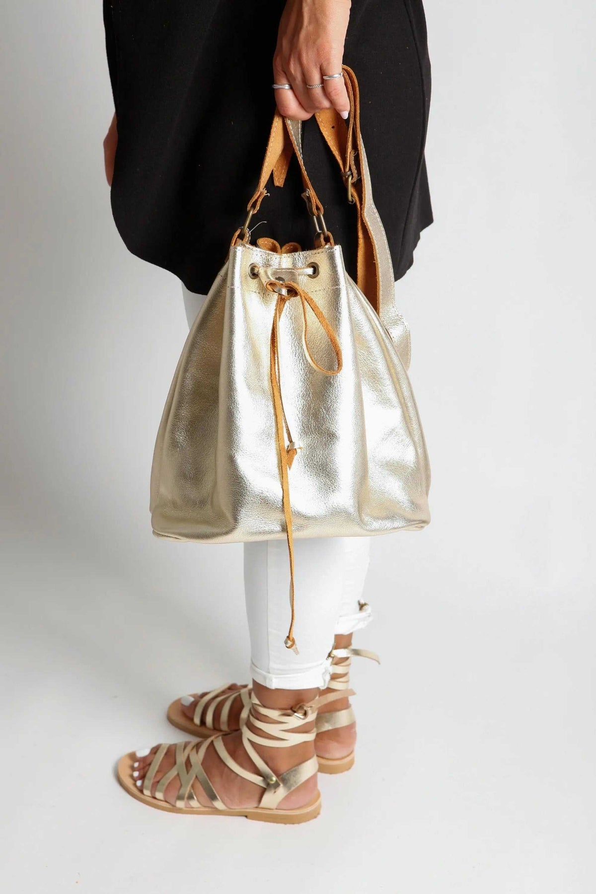 leather women's handbag in metallic gold with a soft bucket shape, tan drawstring and short handles with metal rings