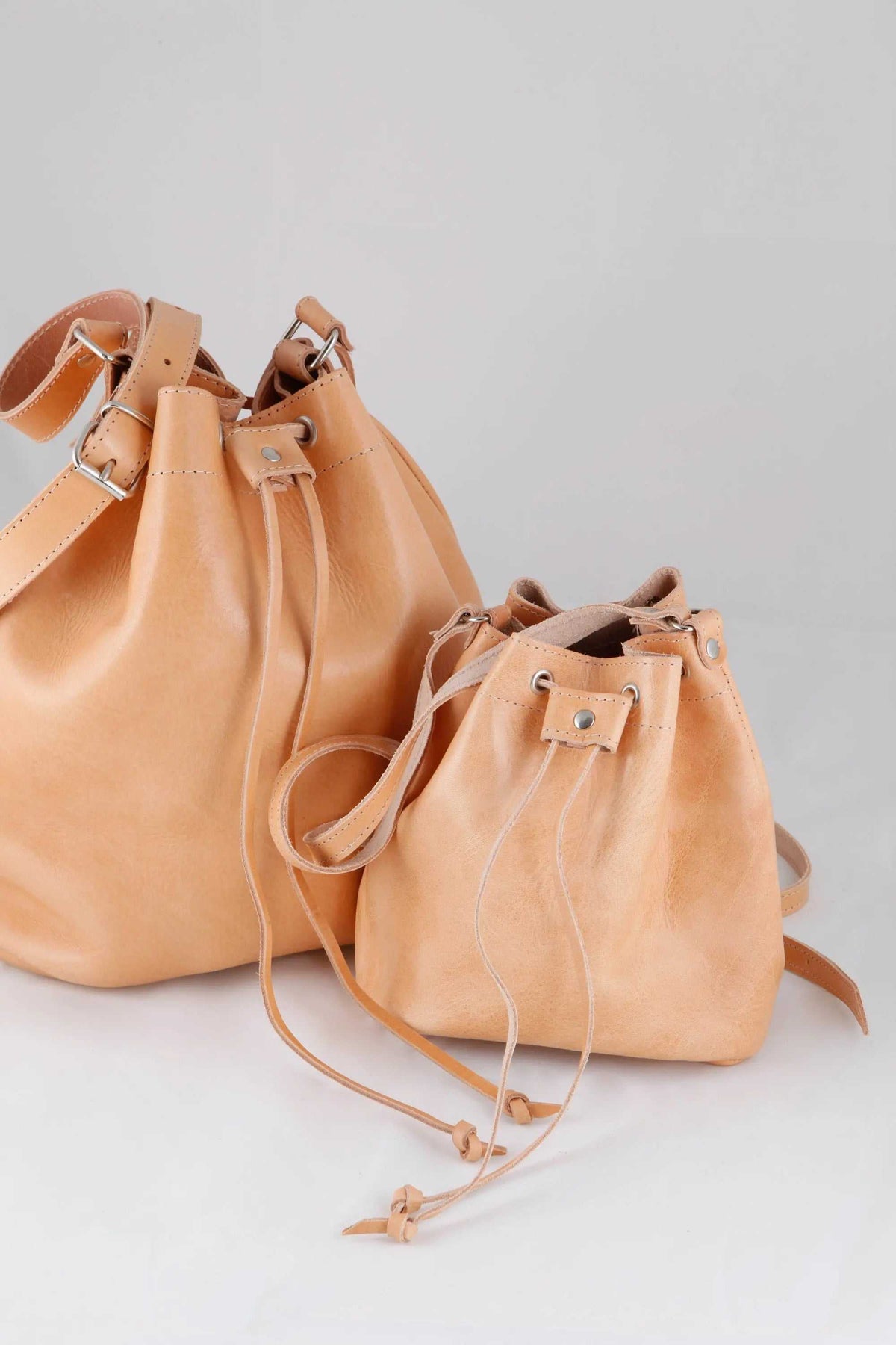 leather women's handbag in warm tan, with a smooth finish, bucket shape, drawstring closure and adjustable strap